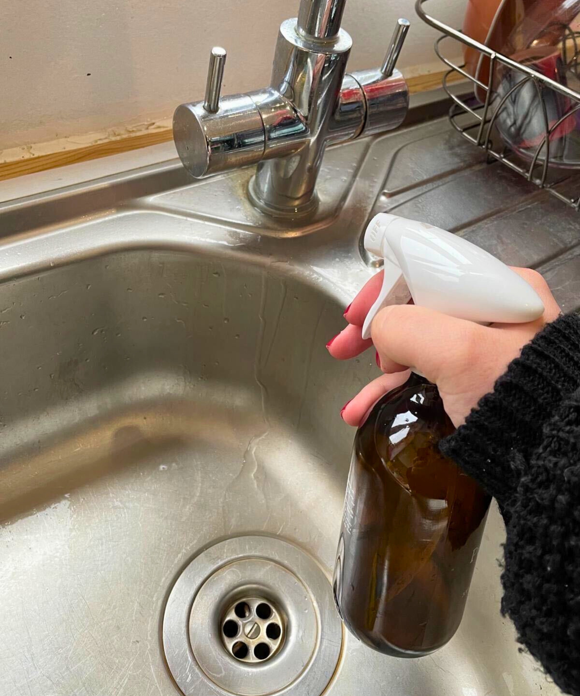 Meine Hand besprüht den Wasserhahn mit meiner Zitronen-Kalk-Reinigungsmischung
