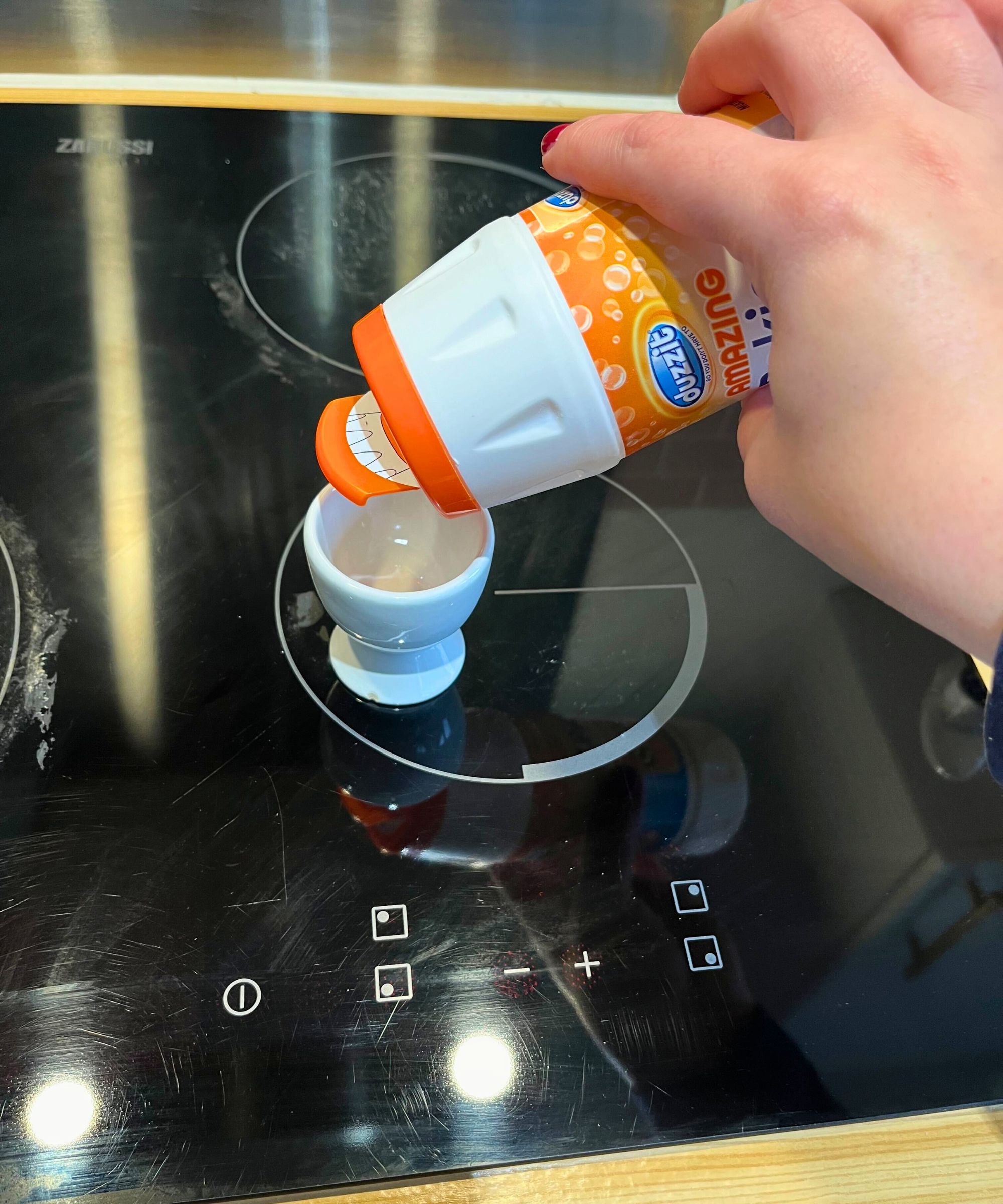 Ich gieße Backpulver aus einer Plastikflasche mit wiederverschließbarem Deckel in einen Eierbecher auf meinem elektrischen Stopper aus schwarzem Glas