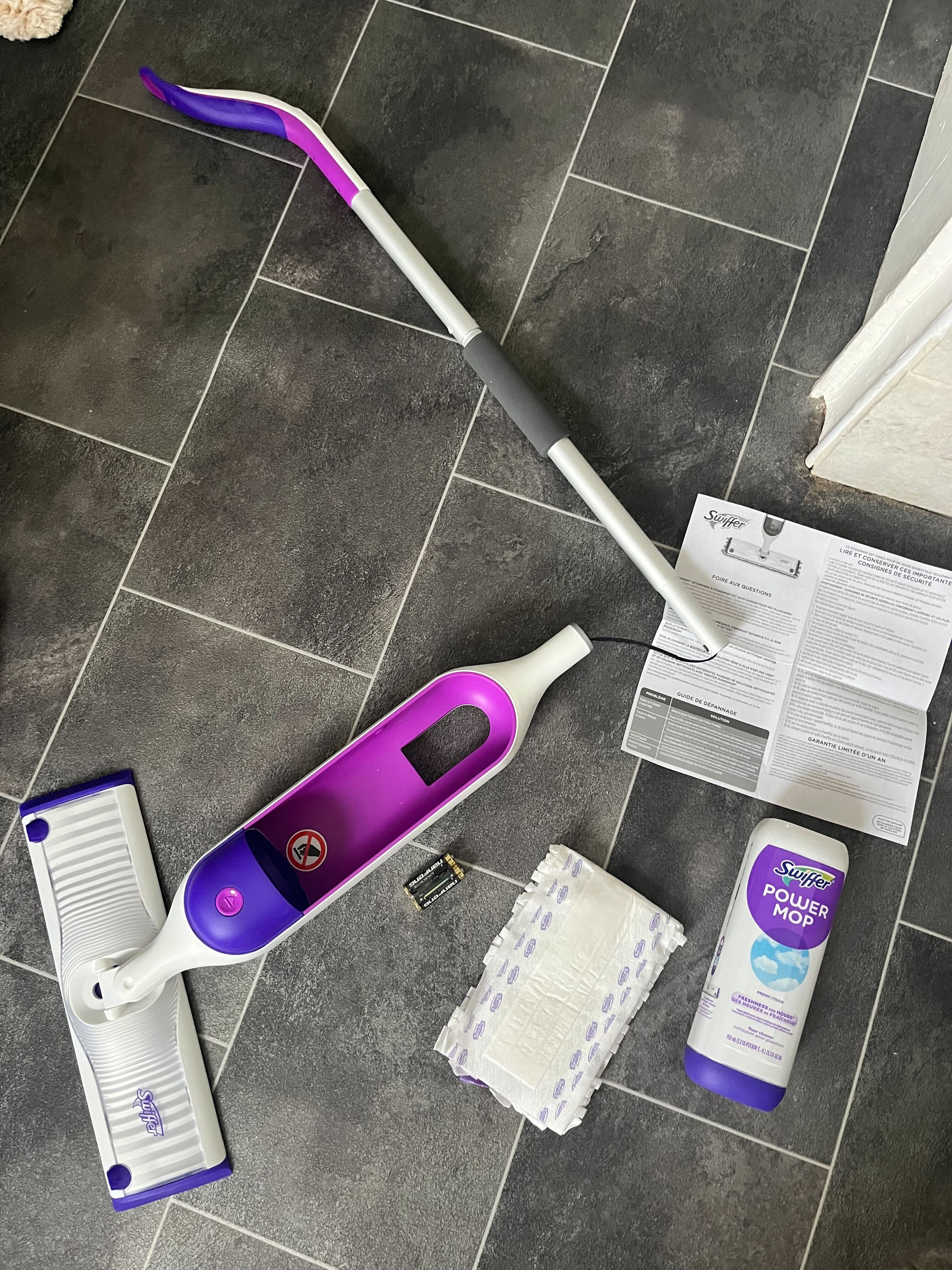 Ein lila-weißer Swiffer Power Mop in Abschnitten auf einem schwarzen Badezimmerboden
