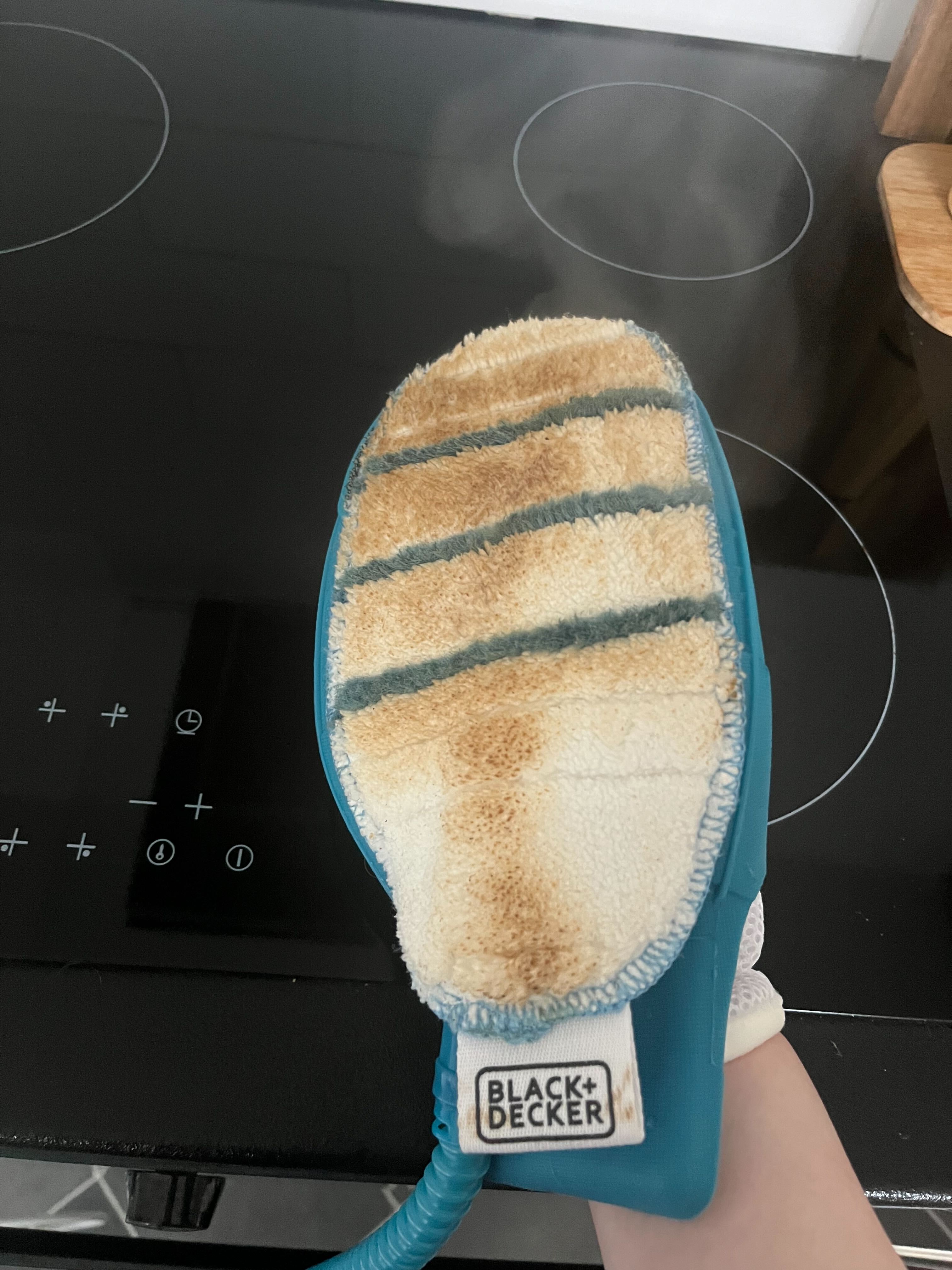 Die Fettflecken einer Ofentür auf einem Dampfreinigungshandschuh
