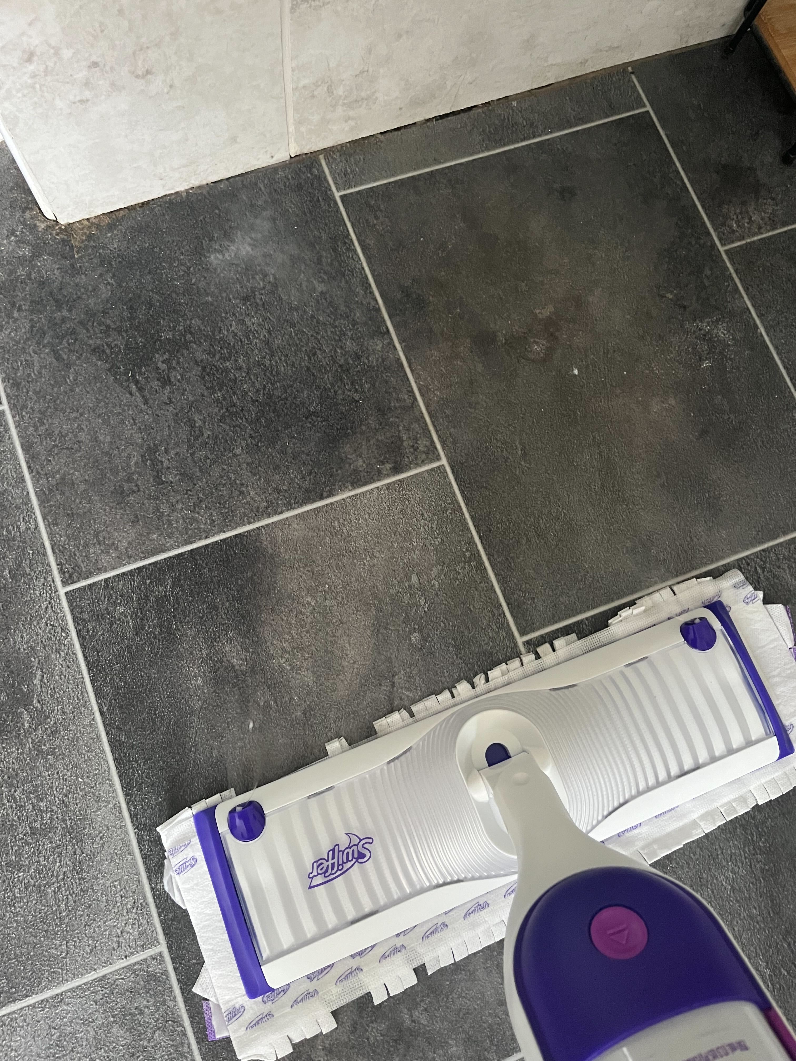 Verwendung eines lila-weißen Swiffer-Wischmopps zum Reinigen eines Badezimmerbodens