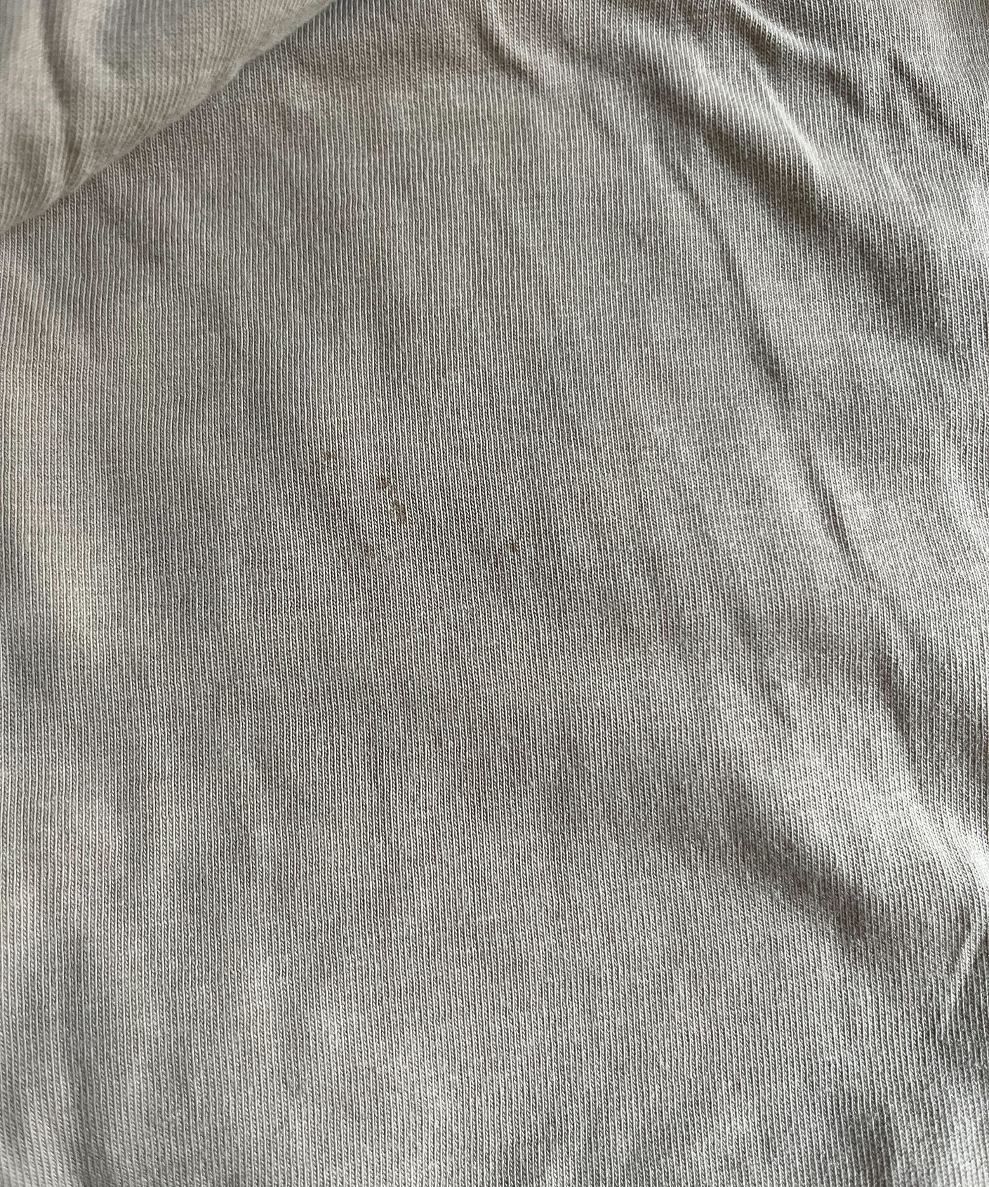 Einige alte, kleine Blutflecken auf einem beige Oberteil