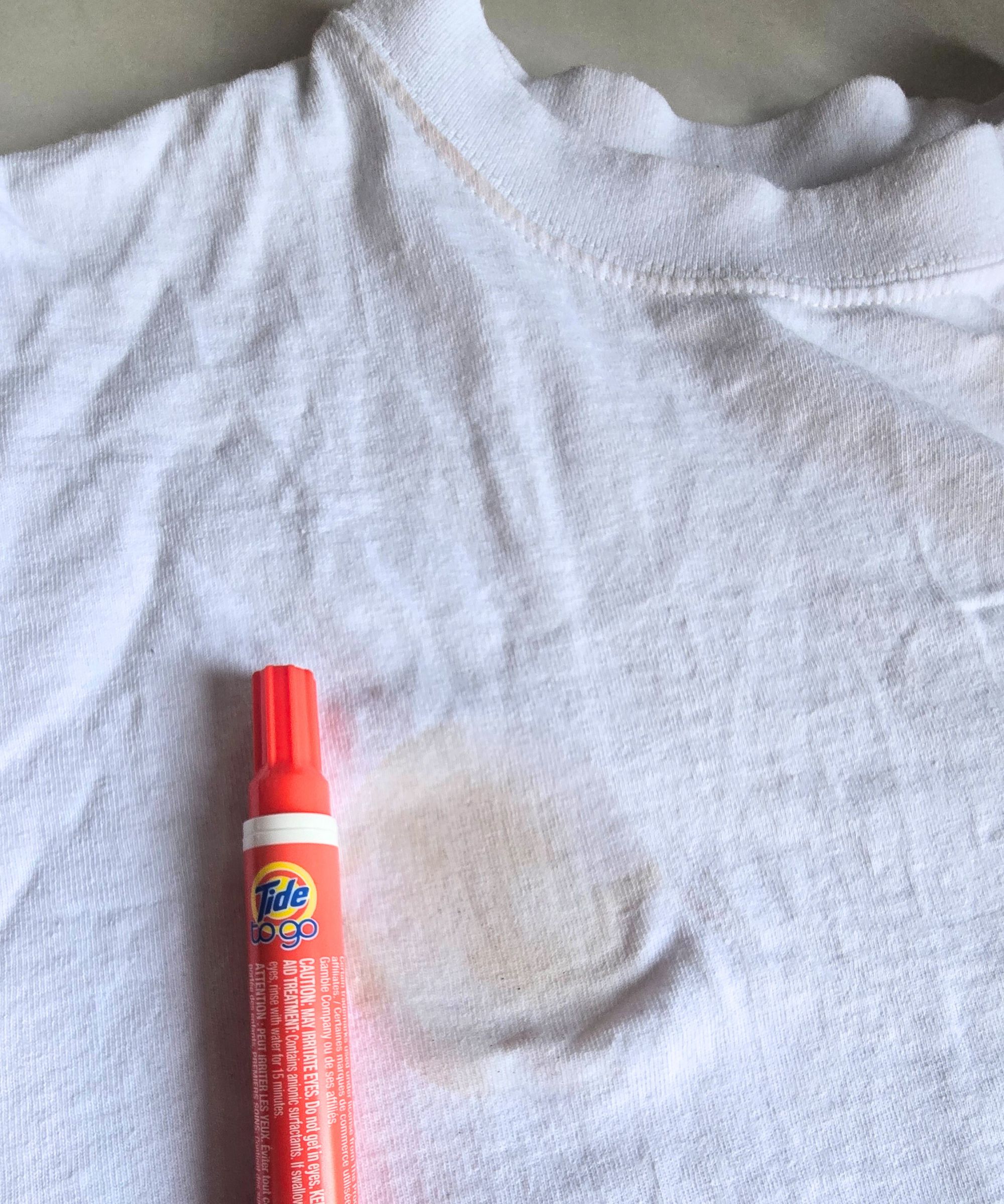 Ein weißes T-Shirt mit einem feuchten Fleck mit einem roten Gezeitenstift daneben