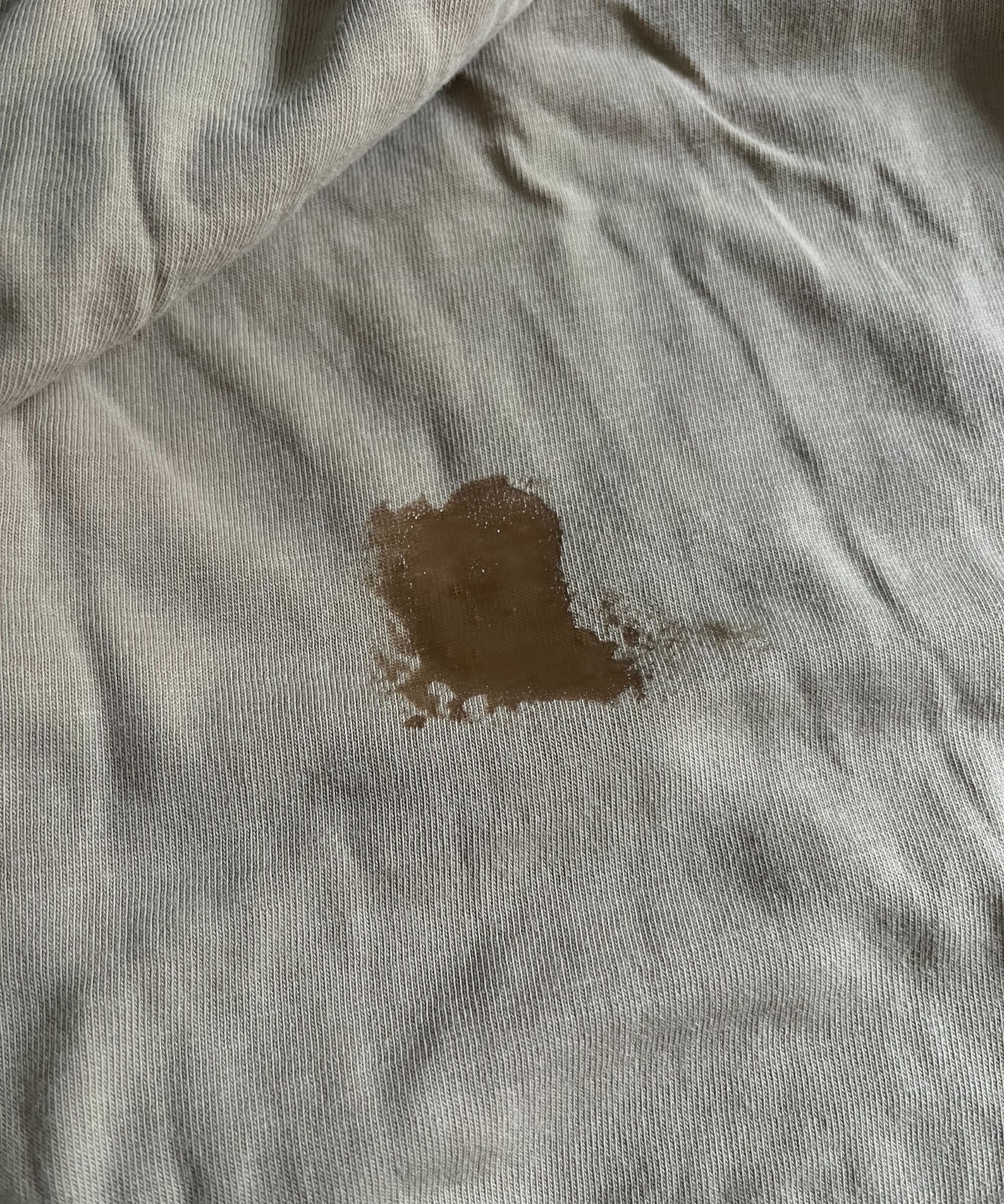Ein nasser Fleck über ein paar alten Blutflecken auf einem beige Oberteil