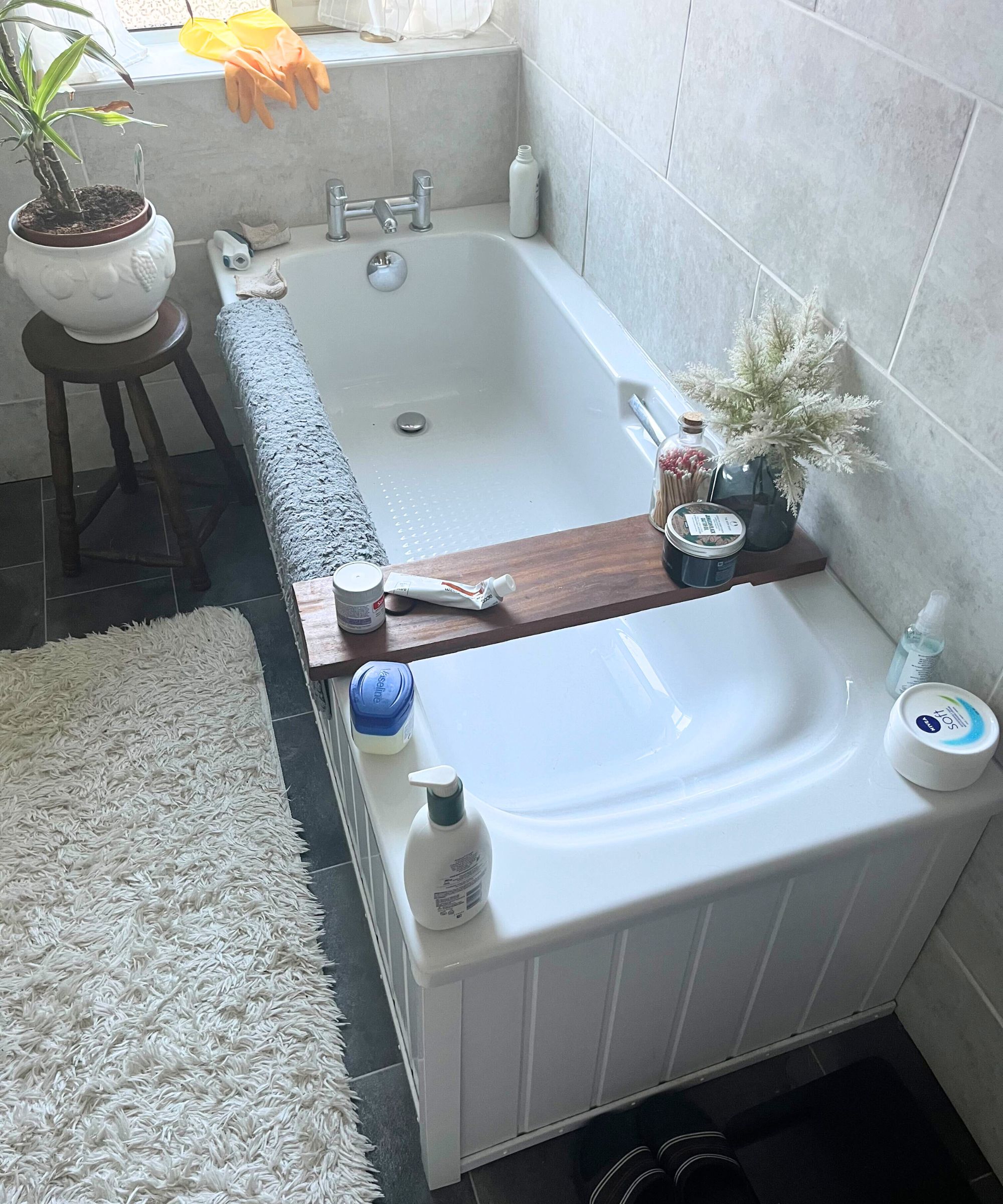 Eine weiße Badewanne, die mit Produktflaschen bedeckt ist. 