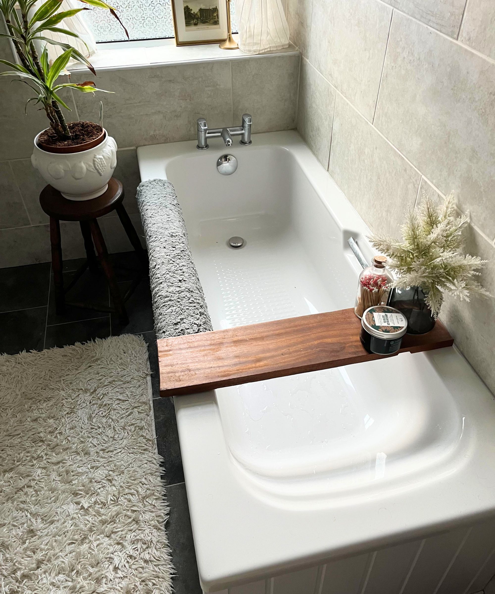 Eine ordentliche weiße Badewanne in einem gefliesten Badezimmer. 
