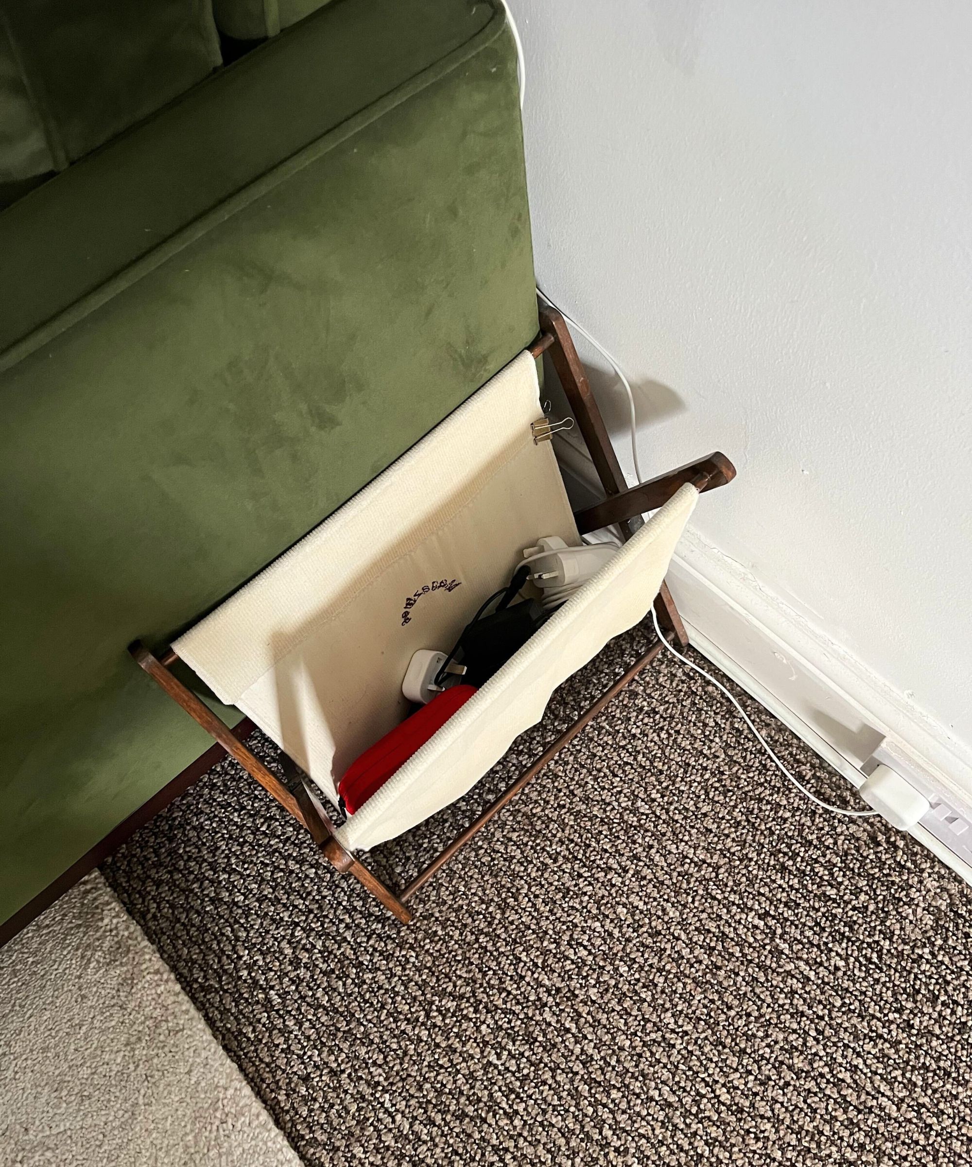 Ein Magazinregal neben einer grünen Samtcouch mit ordentlichen Kabeln im Inneren. 