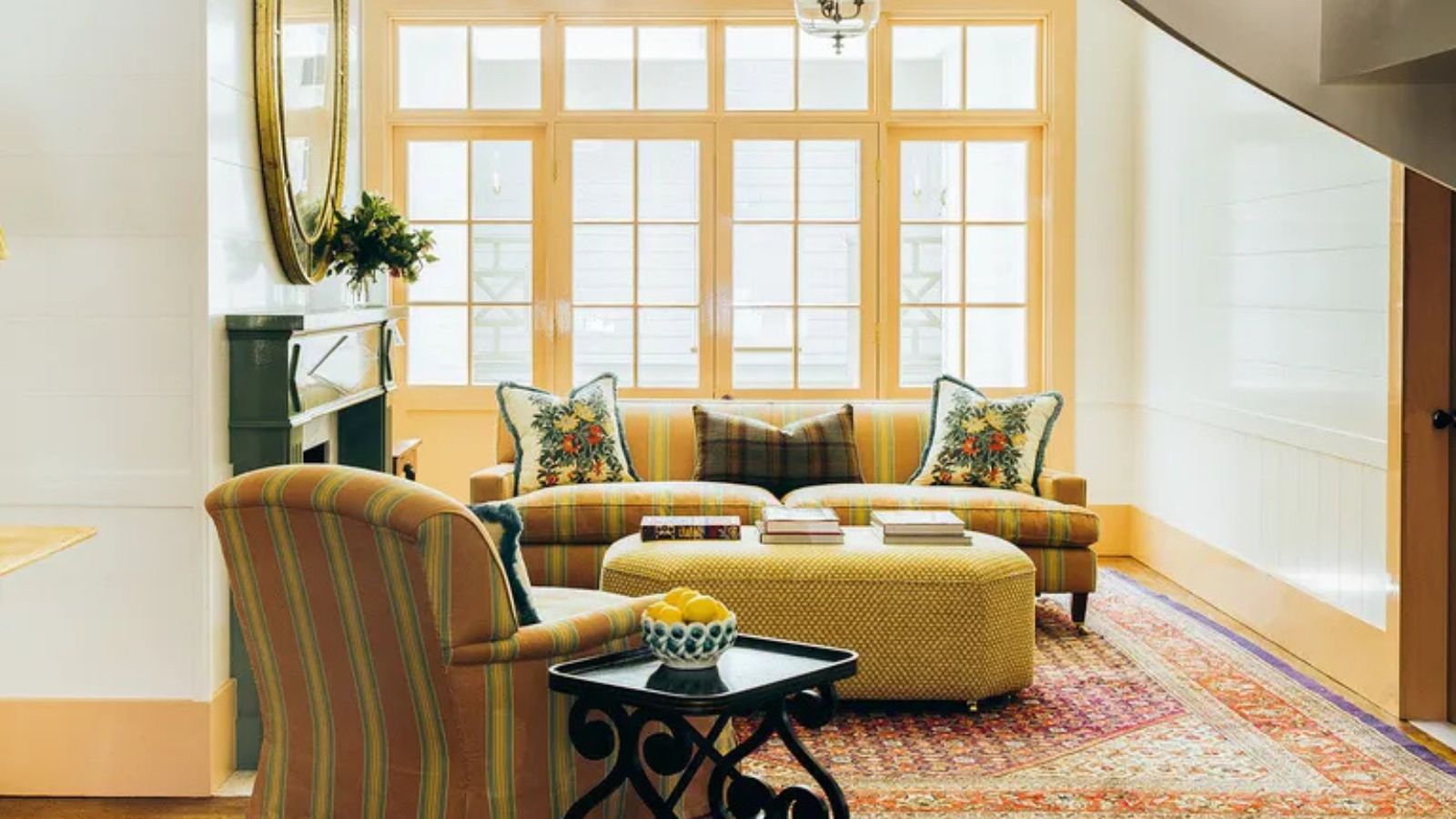 neutral and yellow living room with matching yellow woodboard and french doors with yellow striped upholstered couch and coordinating armchair and a yellow ottoman