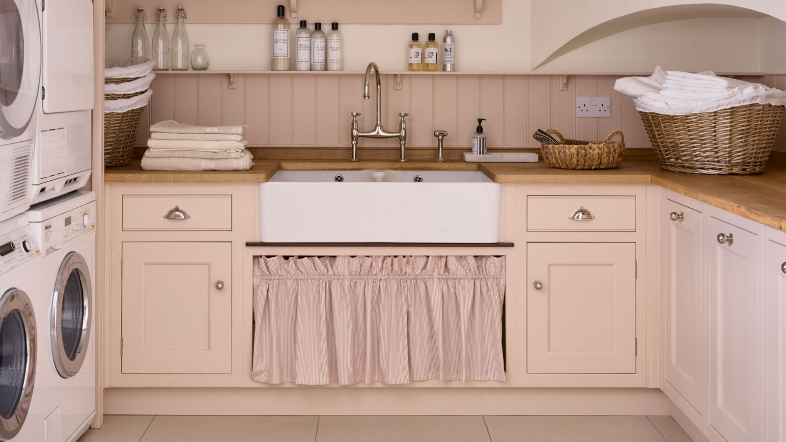 pink laundry room with a farmhouse sink, and a curtain cabinet below.