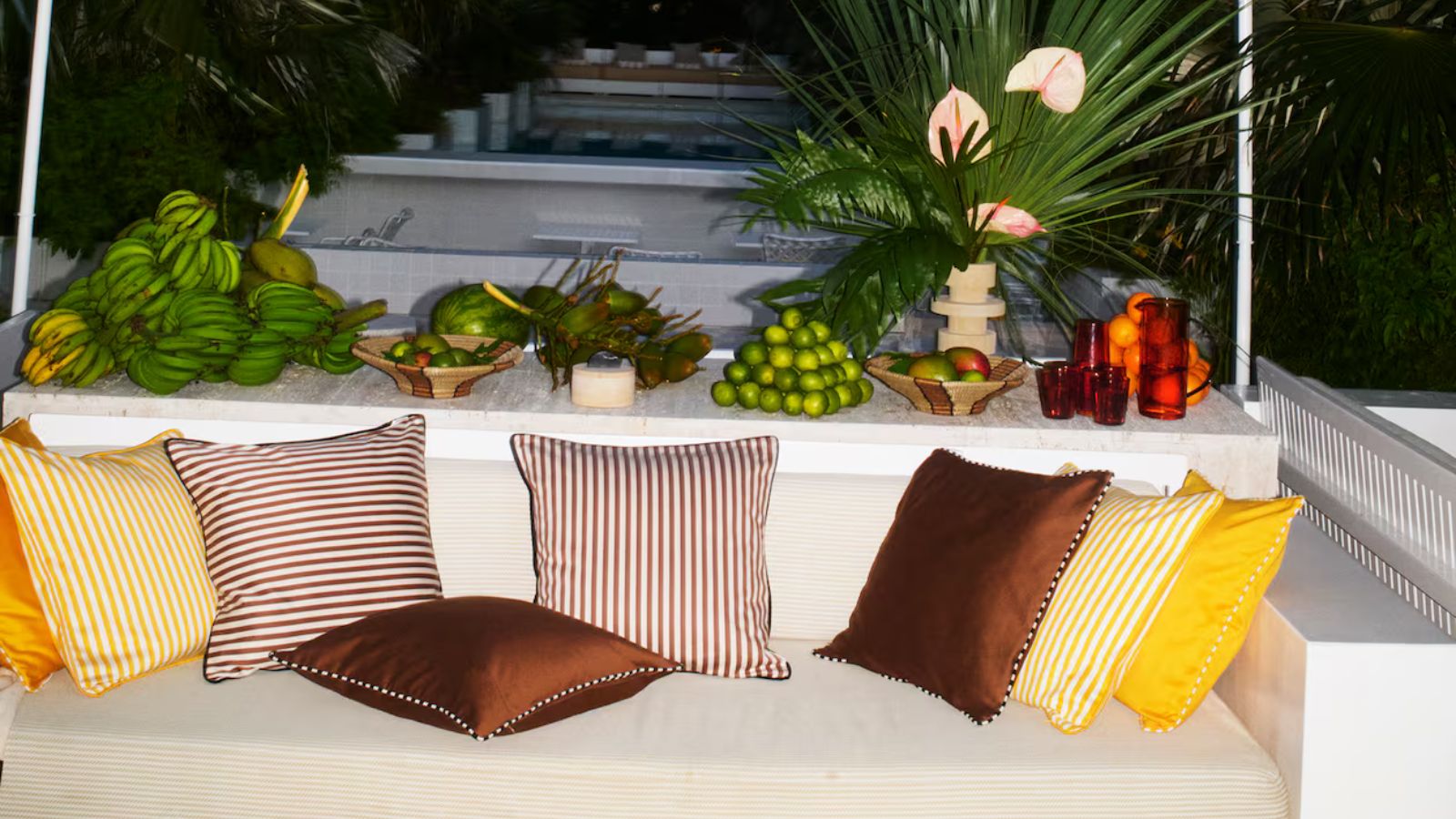 Banquette seating outside with brown and yellow striped cushions and white and yellow parasols