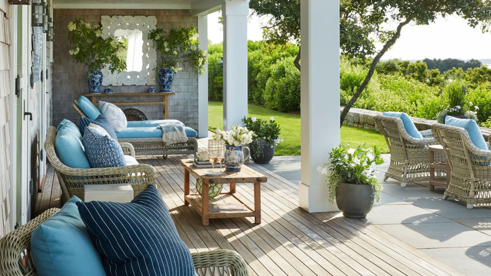 Porch with rattan loungers, daybeds and blue cushions and wood decking