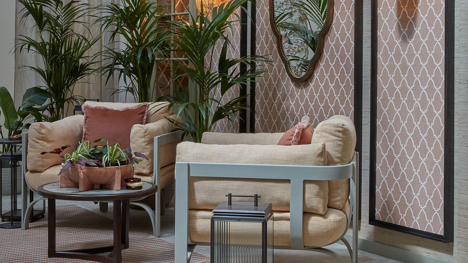 A courtyard garden with two large armchairs and a coffee table, with planters and lanterns