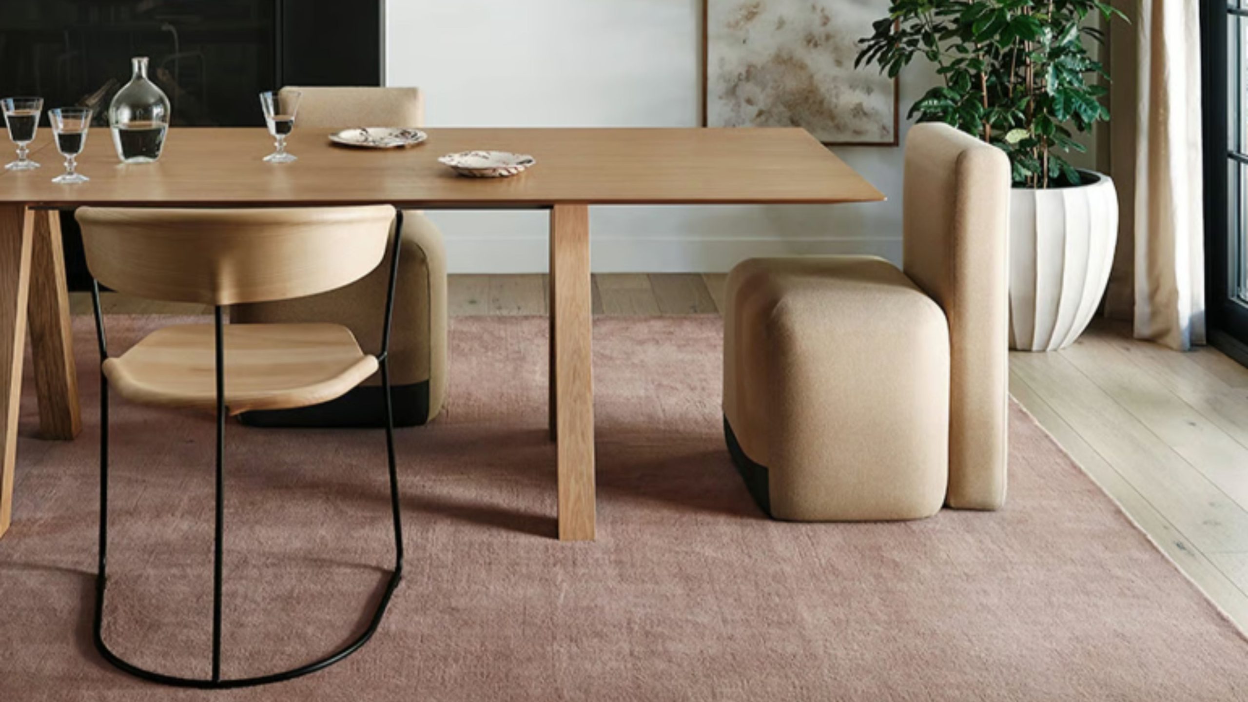 Ashley Tisdale x Rugs USA blush toned wool rug anchors a sleek wooden dining table and modern chair set in a sunlit dining room
