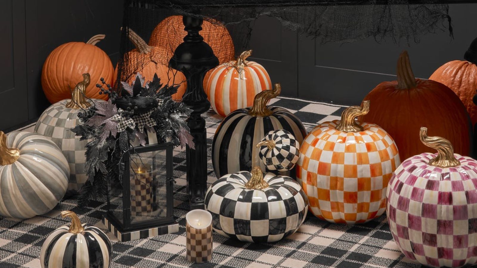 Collection of black, orange, grey and purple checkered and striped resin pumpkins on a black and white tartan rug