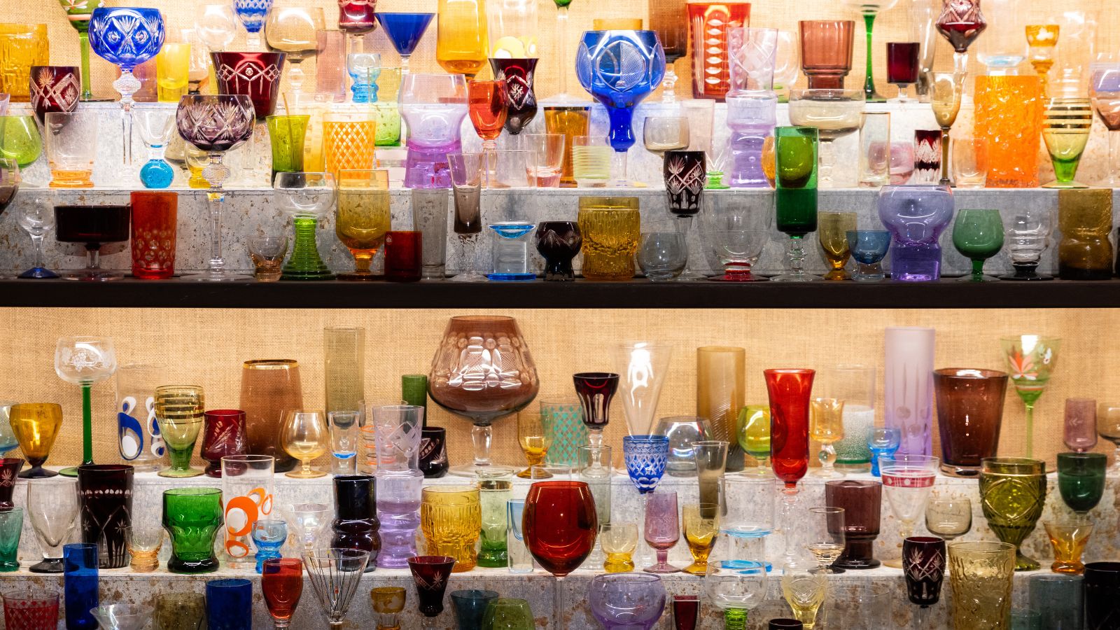 An array of colored vintage glasses on shelves