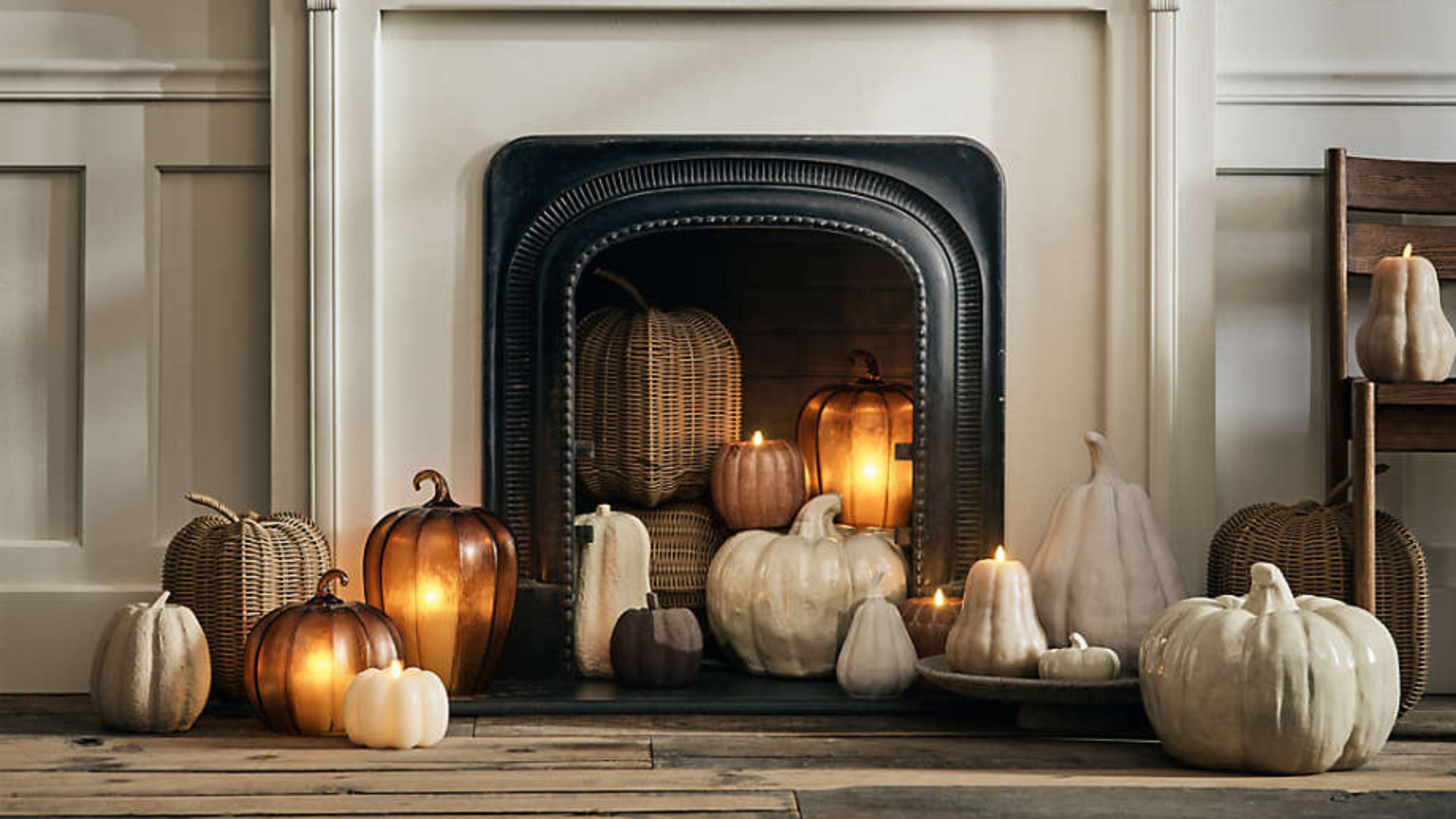 Crate &amp; Barrel fall 2025 pumpkin decorations in wicker, ceramic, and papier mache inside of a cream and black fireplace.