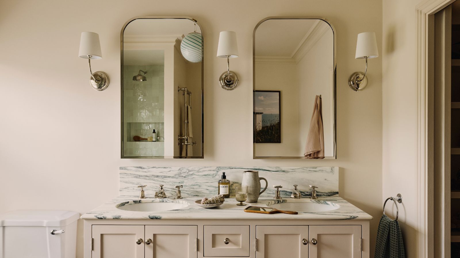 A double sink bathroom vanity with two mirrors, and three wall sconces.