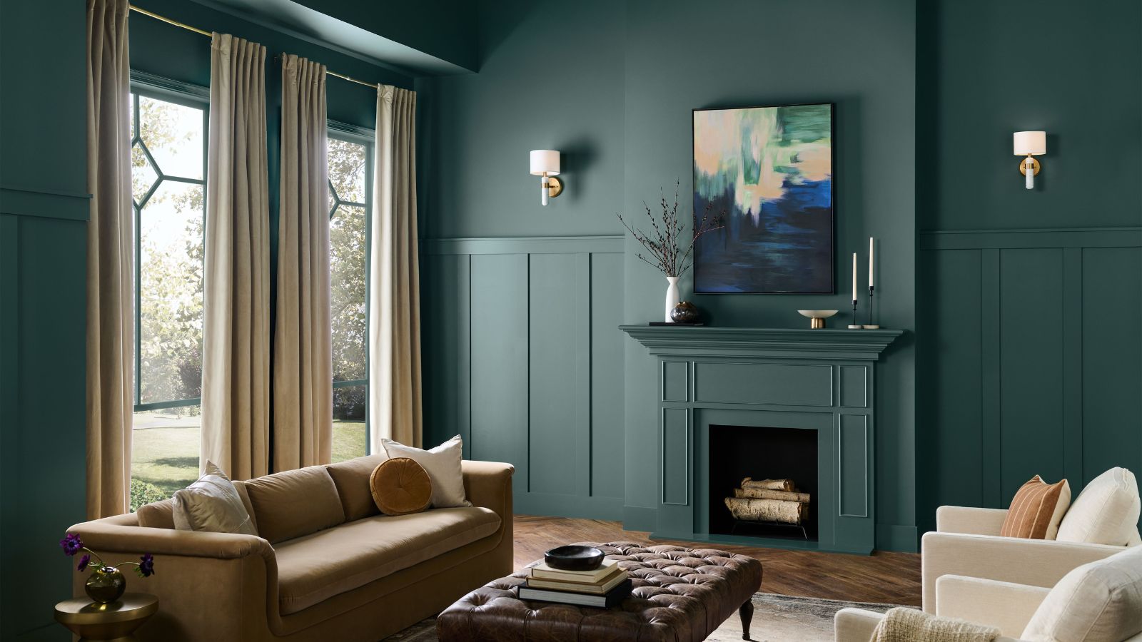 Deep green painted living room with fireplace, large windows, beige sofa, leather ottoman and cream armchairs