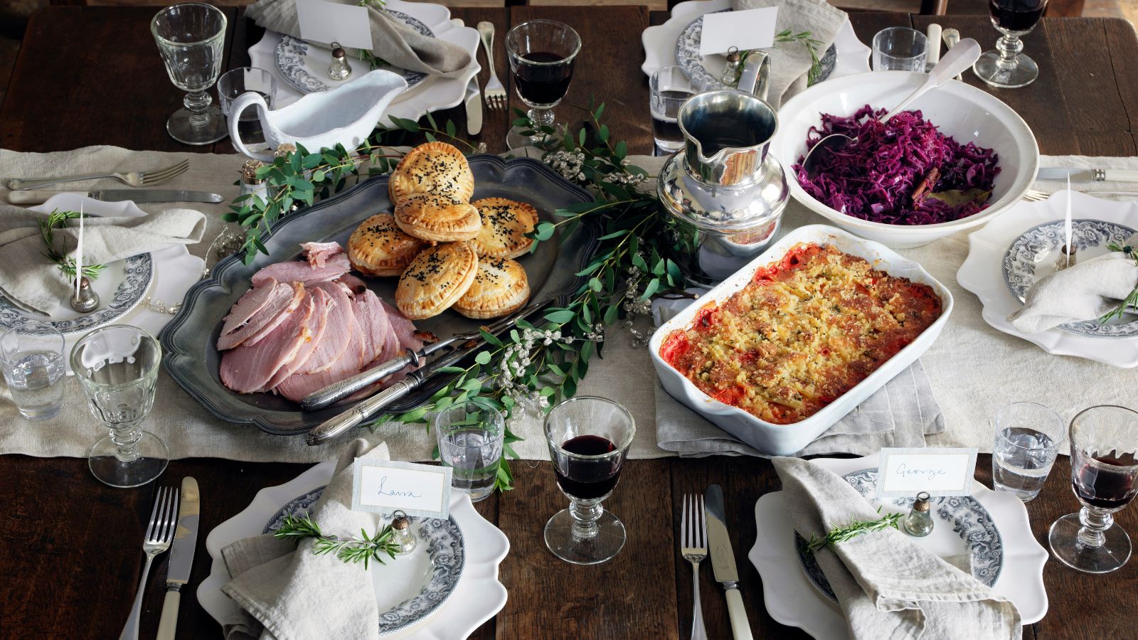 Aerial view of fall dinner with ham, red cabbage and casserole, with white plates and a white linen table runner