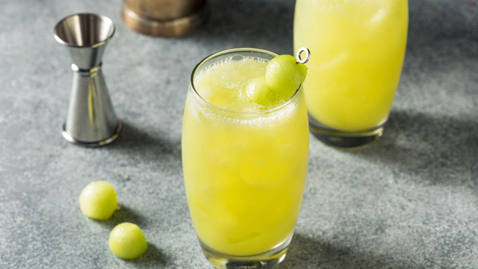 Pale green cocktail with skewered melon balls