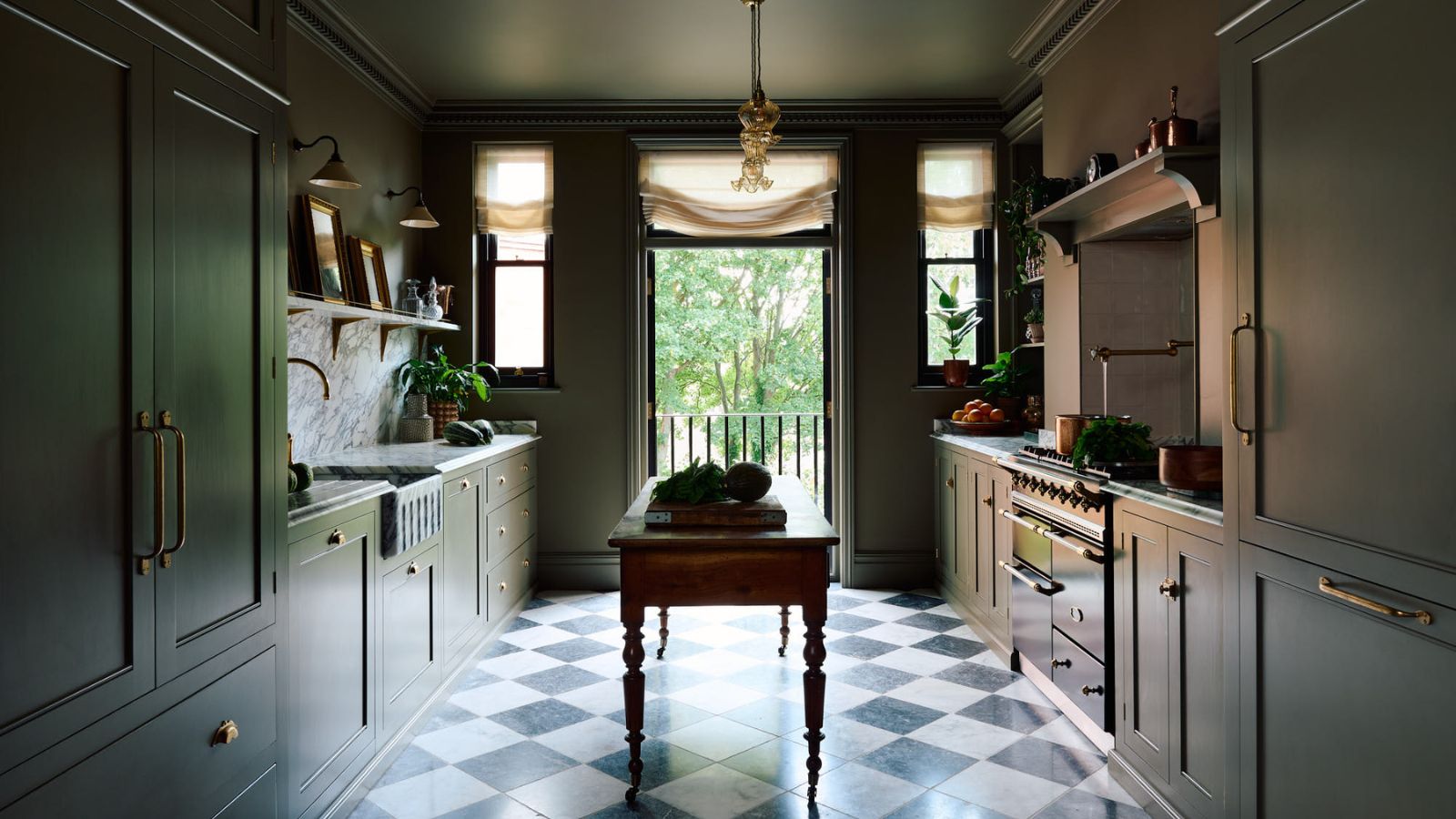 A galley kitchen with green cabinets, checkerboard floor tiles, and a freestanding wooden island
