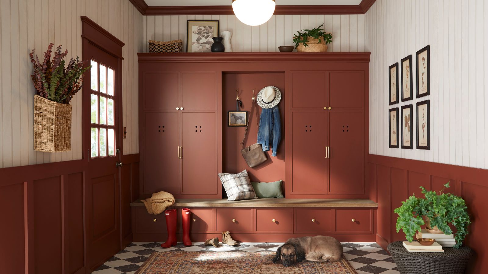 Red-painted mudroom with built-in cabinetry, checkerboard tile floor, wood panelled white walls and plants