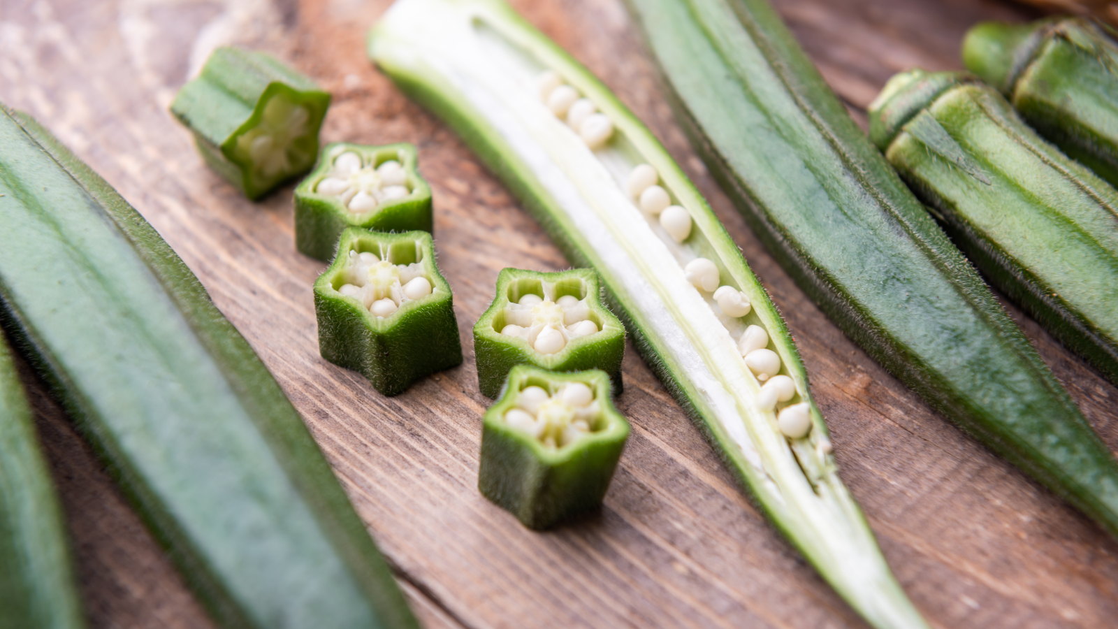 Fresh okra sliced open on a wooden table
