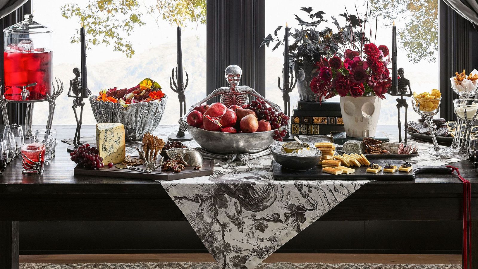 Halloween table with black and white toile runner, chrome serveware, and skull-shaped vases