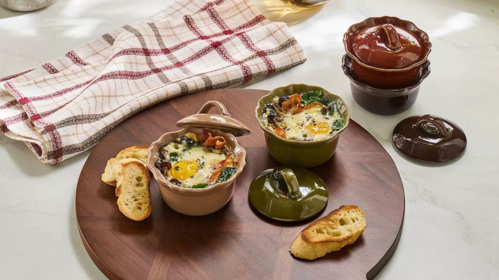 Green, pink and red scalloped ramekins on a round wooden cutting board