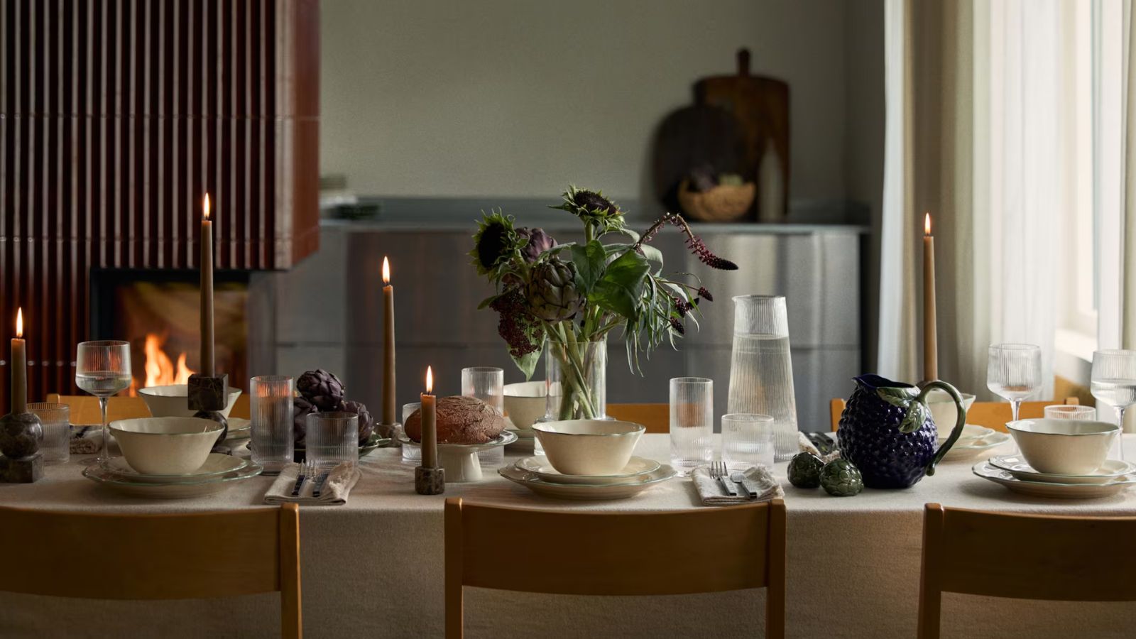 Fall table setting with white tablecloth, white crockery and grape and artichoke-shaped serving bowls