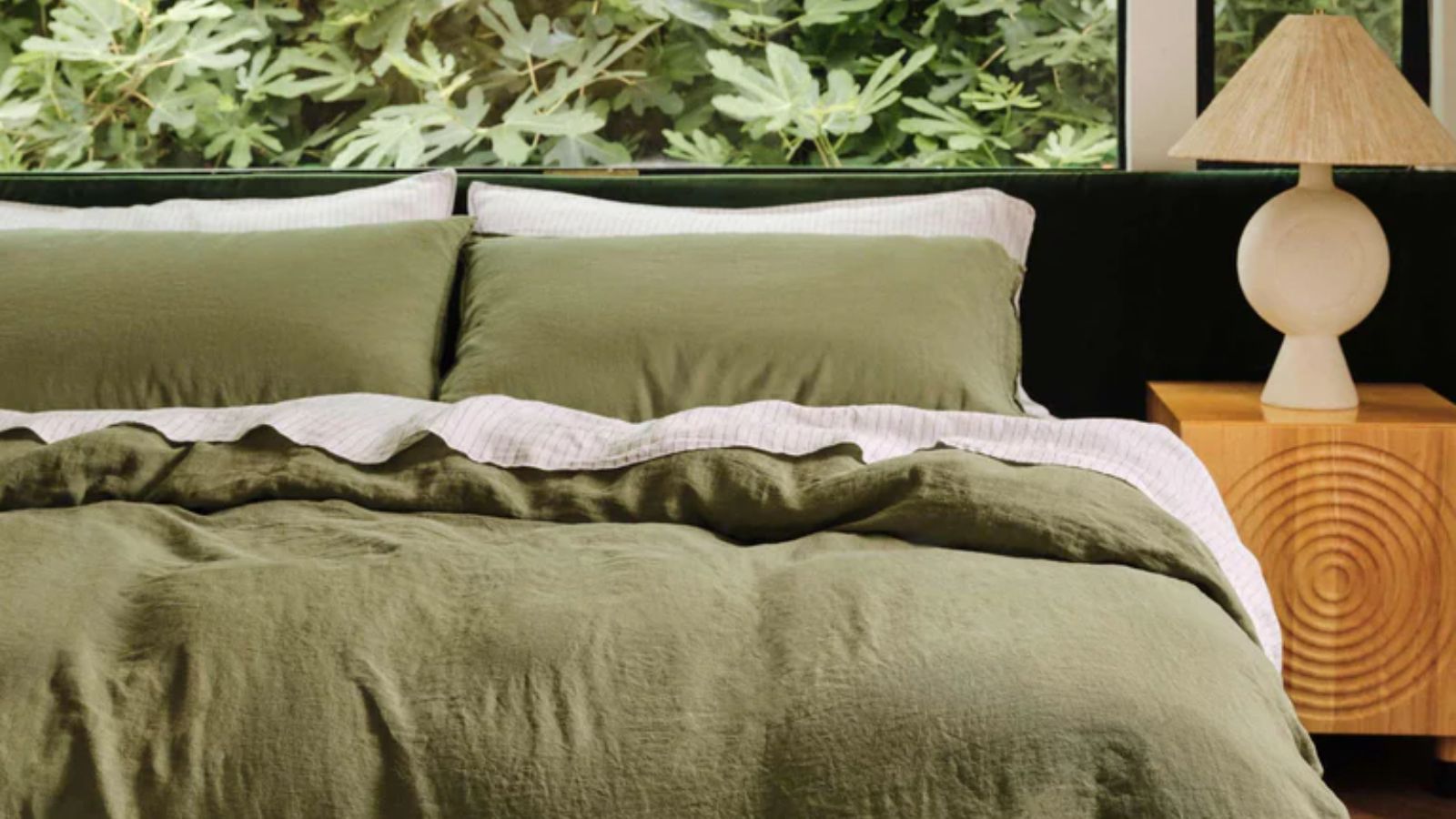 Olive green linen bed sheets with a white striped flat sheet