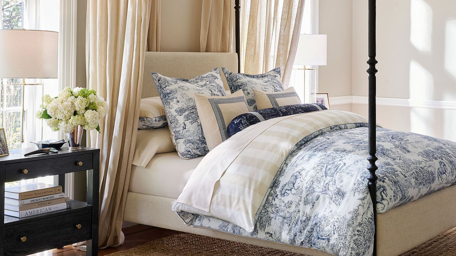 Cream bedframe with blue toile bedding and cream and white striped sheets
