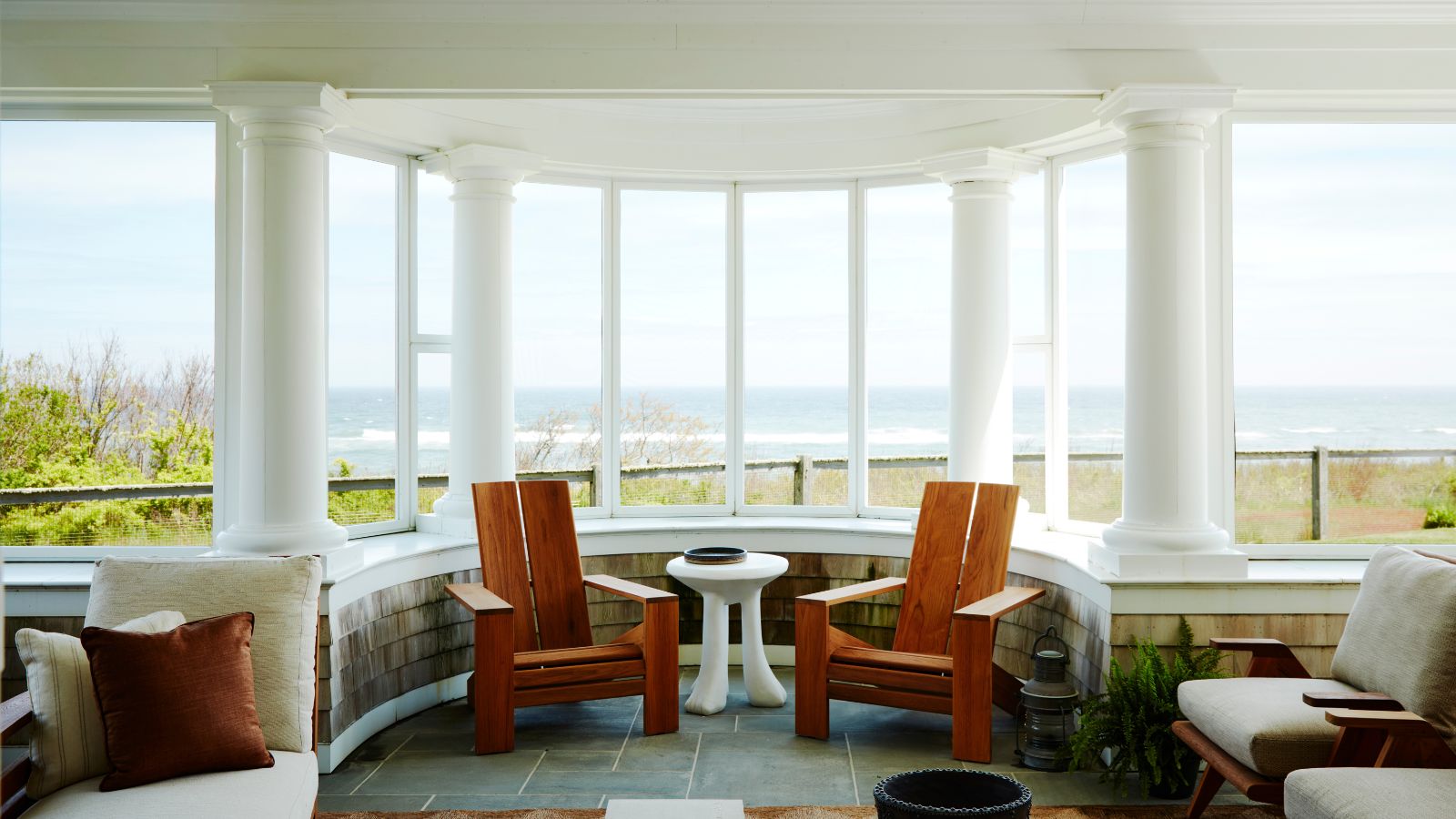 Porch with columns, tiled floor and wooden adirondack chairs