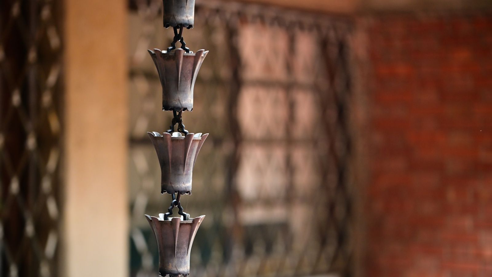 Traditional rain chain drainage system featuring series of connected cup-shaped or funnel-shaped metal containers