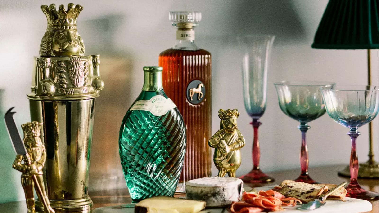 Sideboard with blue and pink iridescent glass coupes, a charcuterie board, and a Nutcracker-inspired cocktail shaker