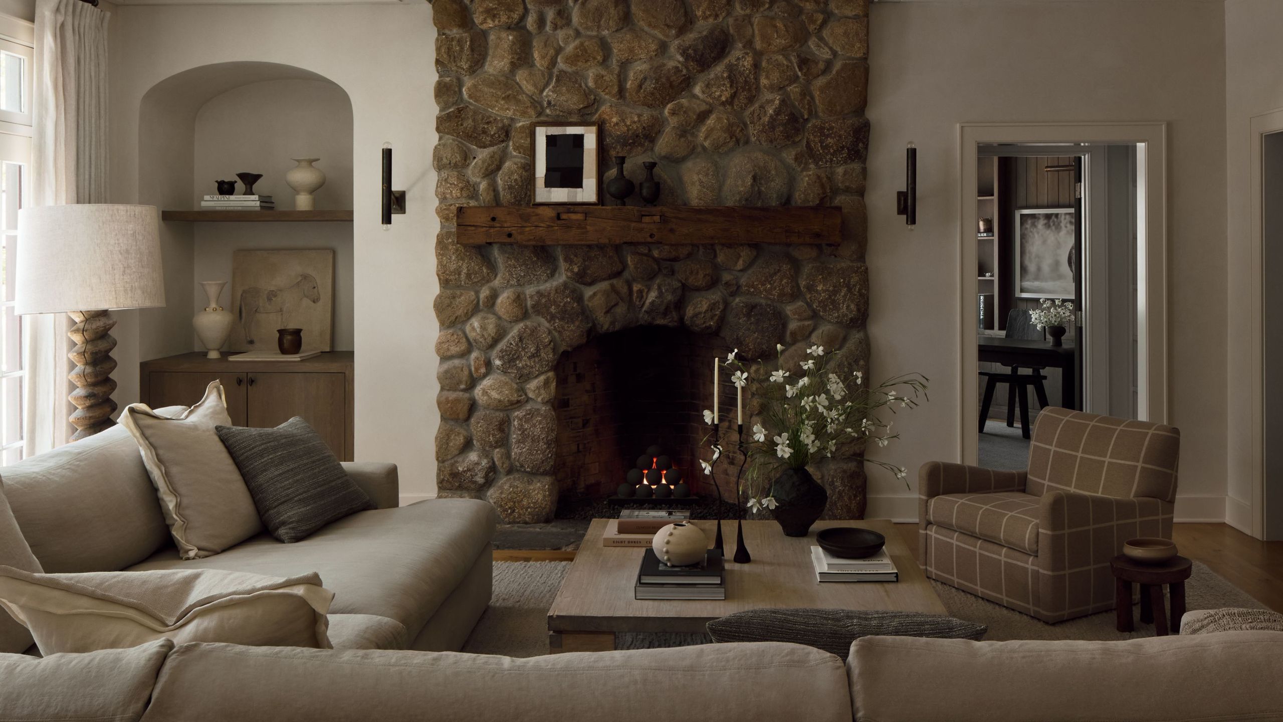 Neutral living room with a large stone fireplace and an arched alcove