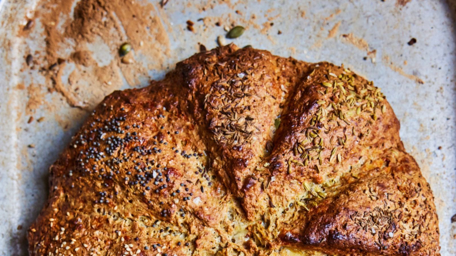 round loaf of seedy homemade bread on a baking tray