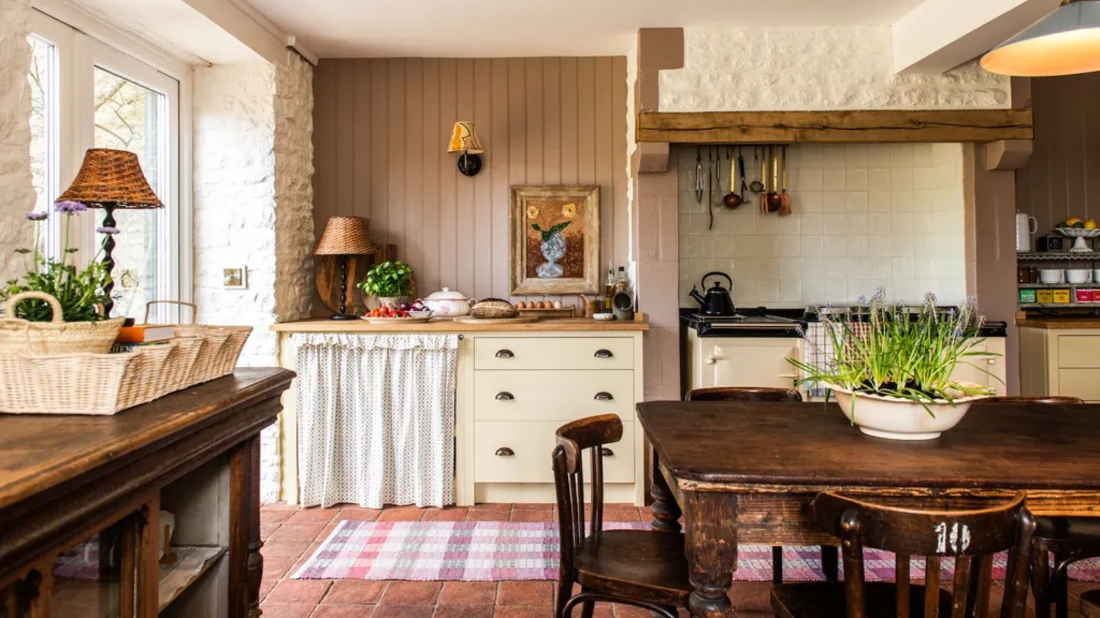 country vintage english kitchen with cream cabinet, dark pink paneled walls, rustic vintage wooden table and chairs