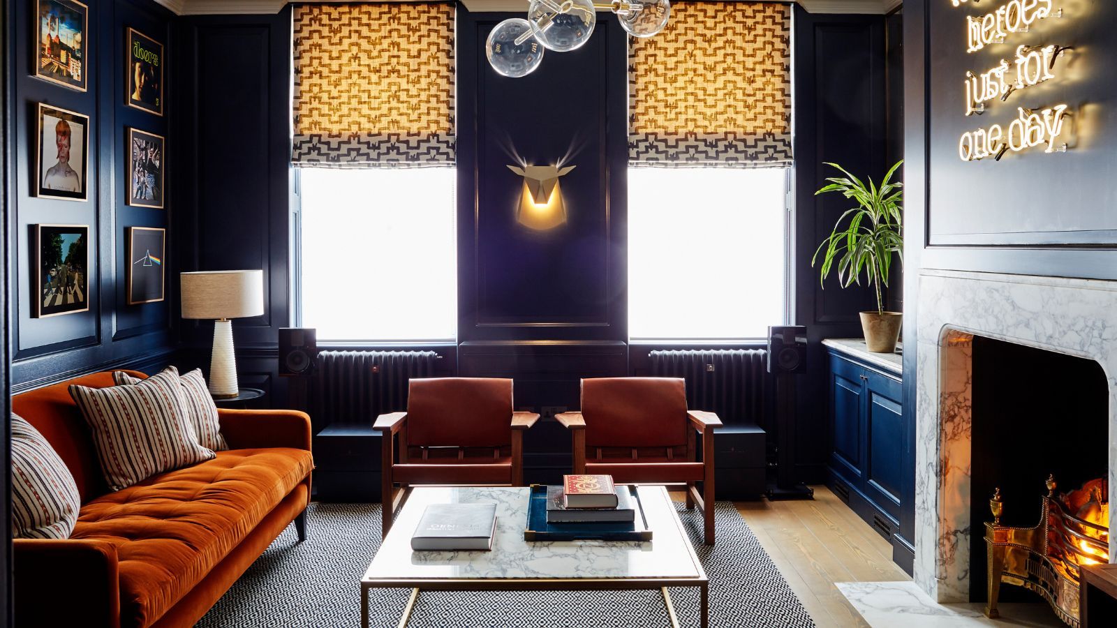 Cozy sitting room with fire lit, dark walls and orange velvet sofa