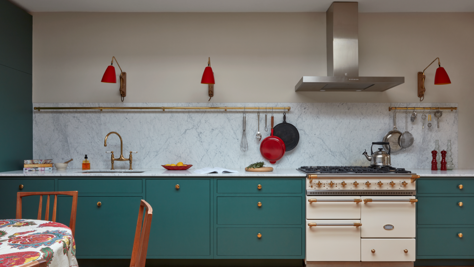 a large kitchen with teal cabinetry, a white oven, red wall sconces, and a white marble backsplash