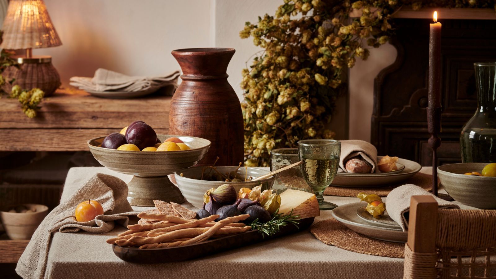 A fall dining table laden with seasonal food in stoneware dishes.