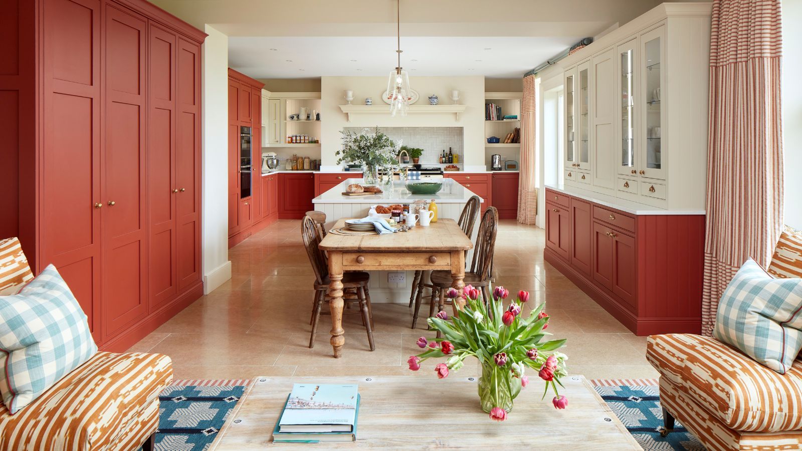 An open plan kitchen and living area with red cabinets and a blue rug beneath the seating area to create zones