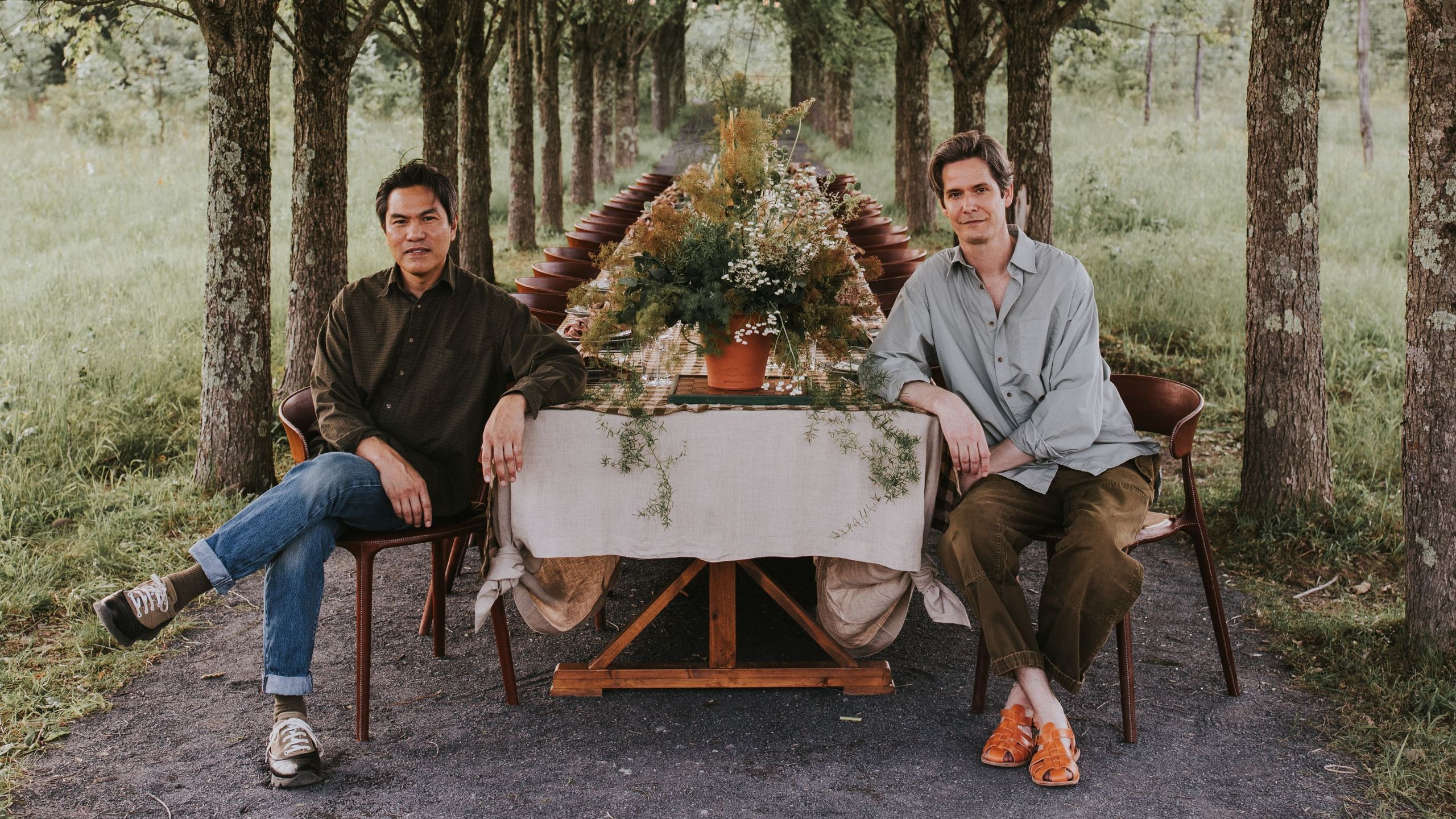 Alan Calpe and Christopher Crawford, founders of Gardenheir sitting at the end of a long dinner table on a tree-lined path