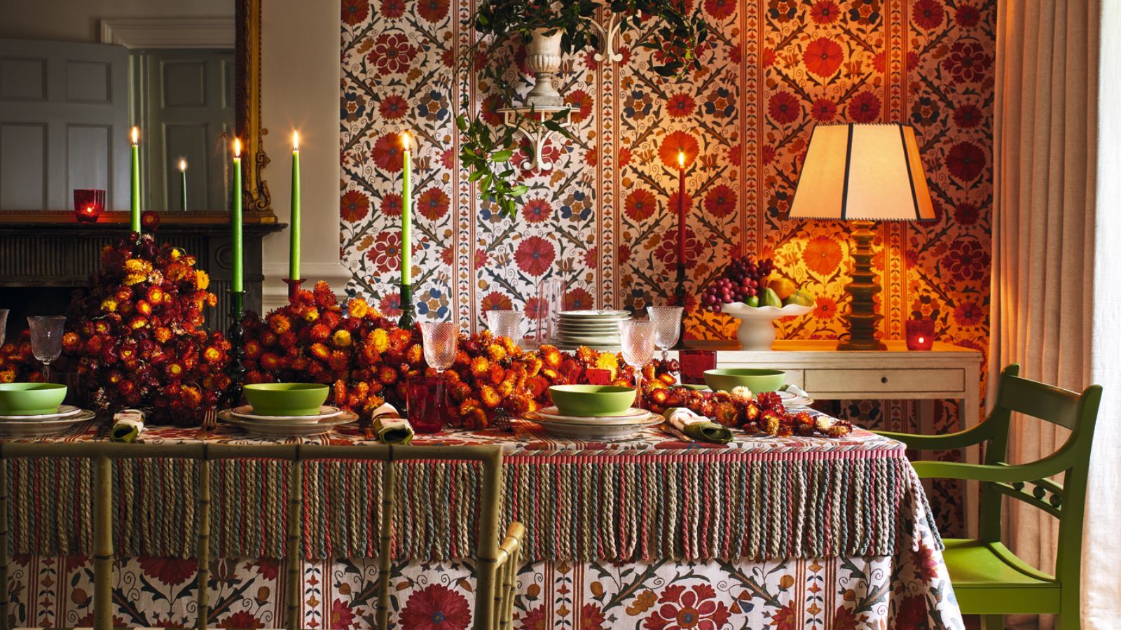 Fall tablescape with lime green and orange color theme, orange flowers on the table, green chairs and patterned linens
