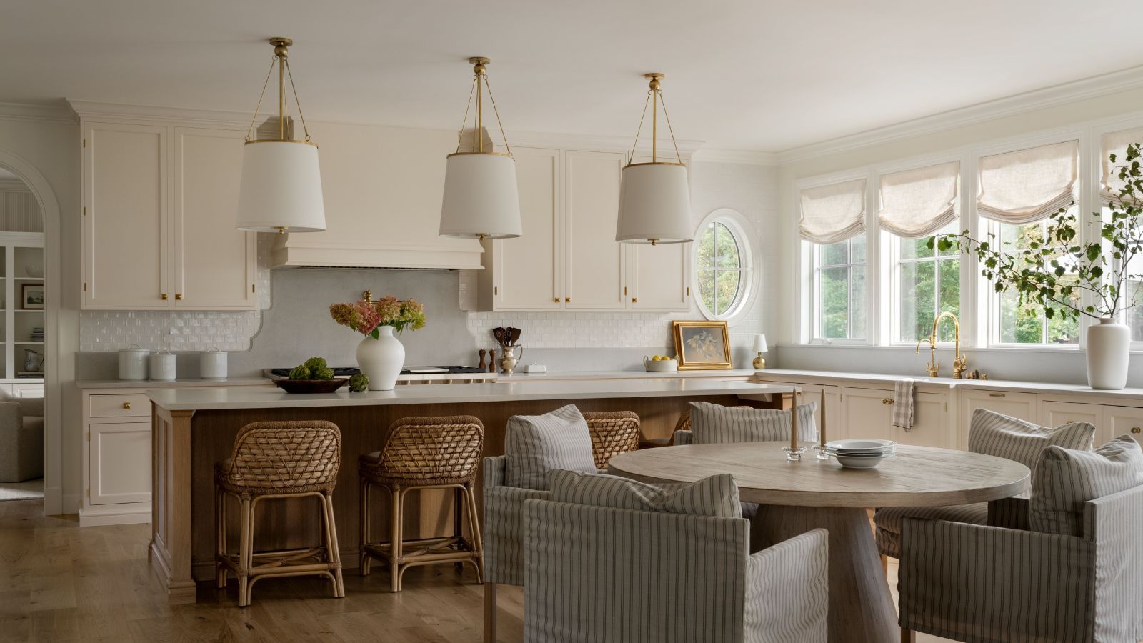 A neutral kitchen with warm white cabinets, a wooden island, and curved profiles throughout the design