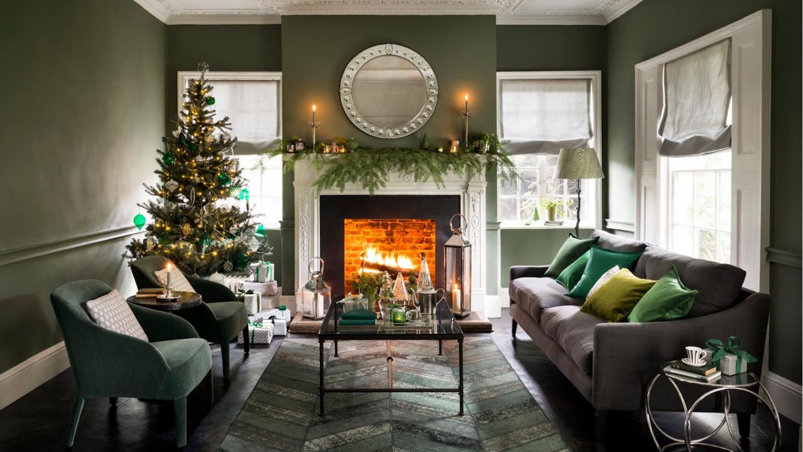 Christmas living room with green walls. Garland on the mantelpiece and Christmas tree in the corner