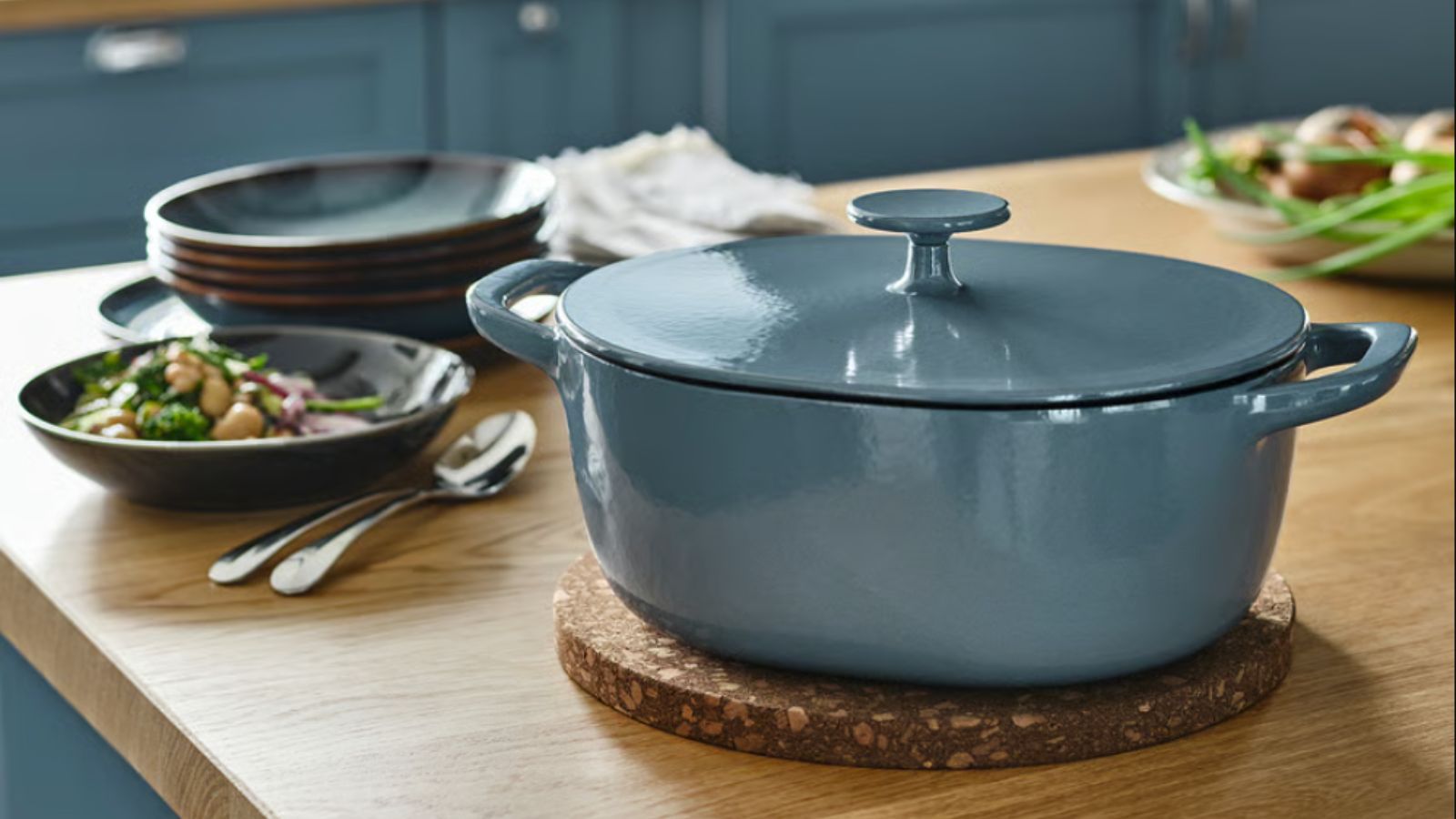 Grey Dutch oven on a kitchen surface with a bowl of food next to it