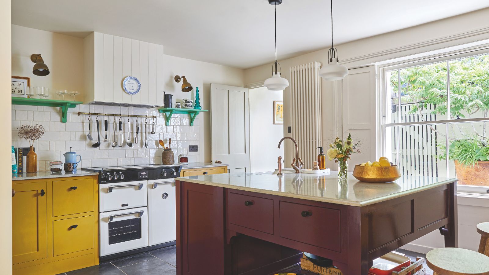 Kitchen with maroon painted island, range oven, white tiled backsplash, and mustard yellow painted cupboard