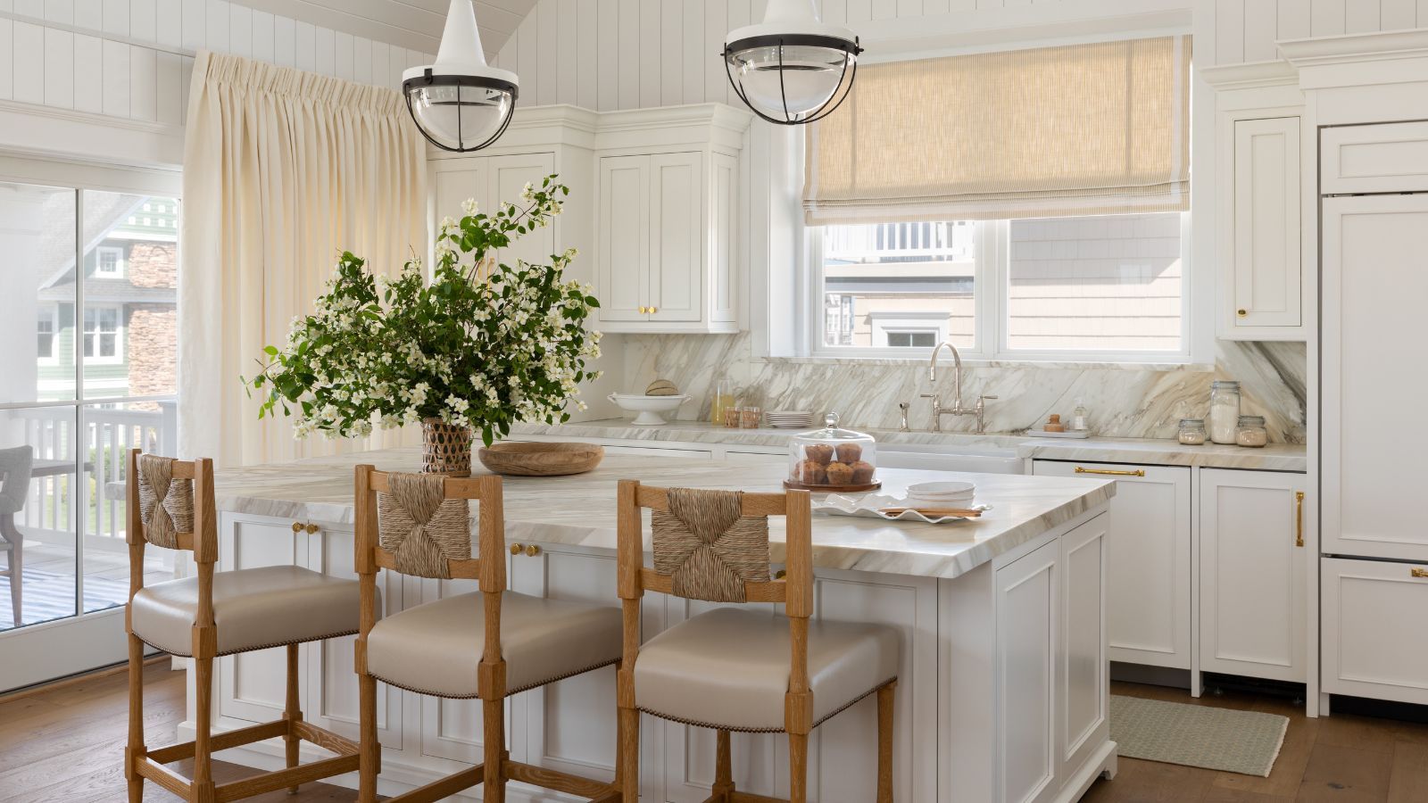 timeless white kitchen with marble countertops wood counter stools and a kitchen curtain