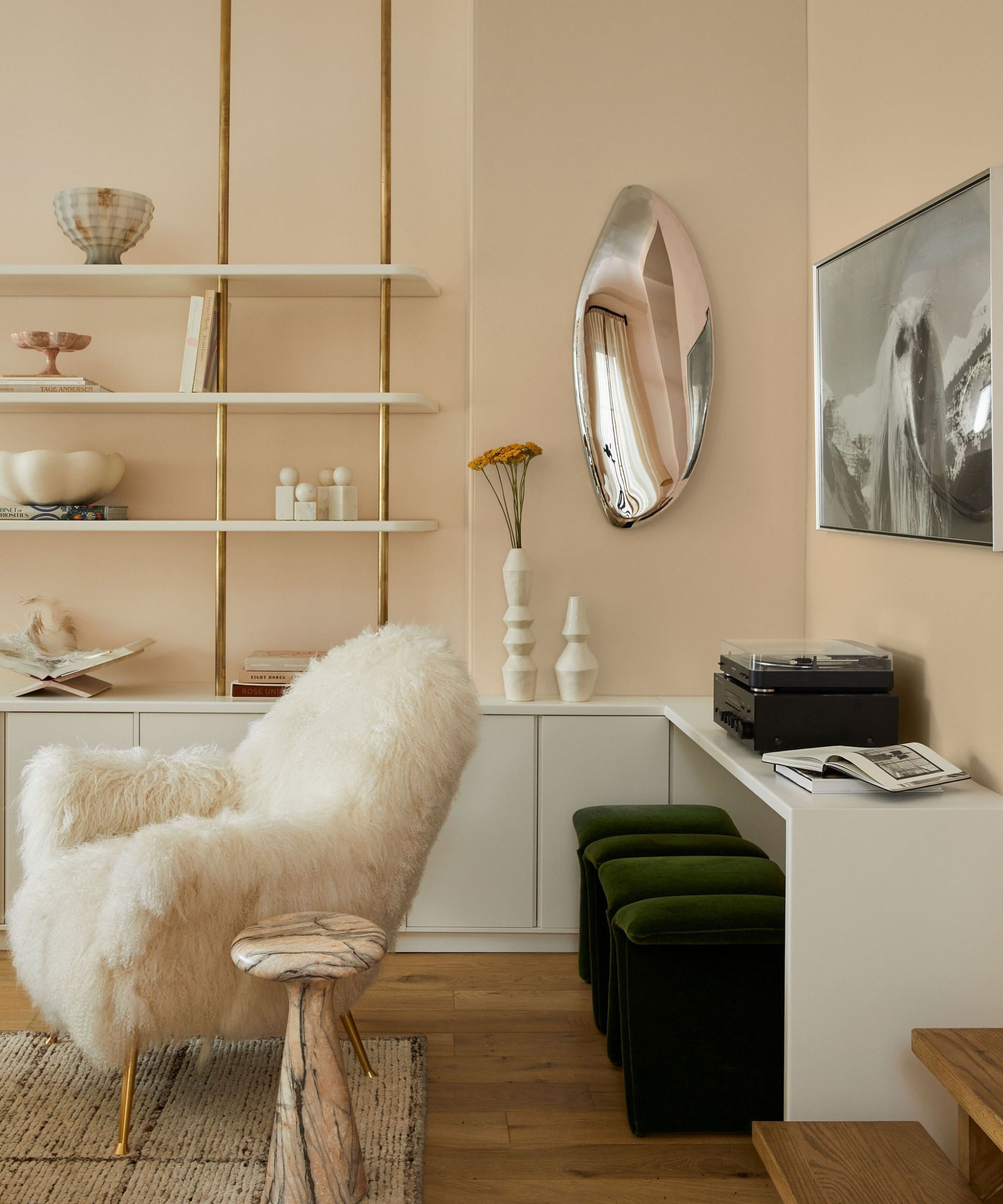 Ein neutrales Wohnzimmer mit großen schwarzen Metallfenstern, die eine Wand einnehmen. Es gibt ein großes beiges Sofa, auf dem ein Hund sitzt, und auf der linken Seite einen Baum. Vorne steht ein großer Couchtisch aus Holz